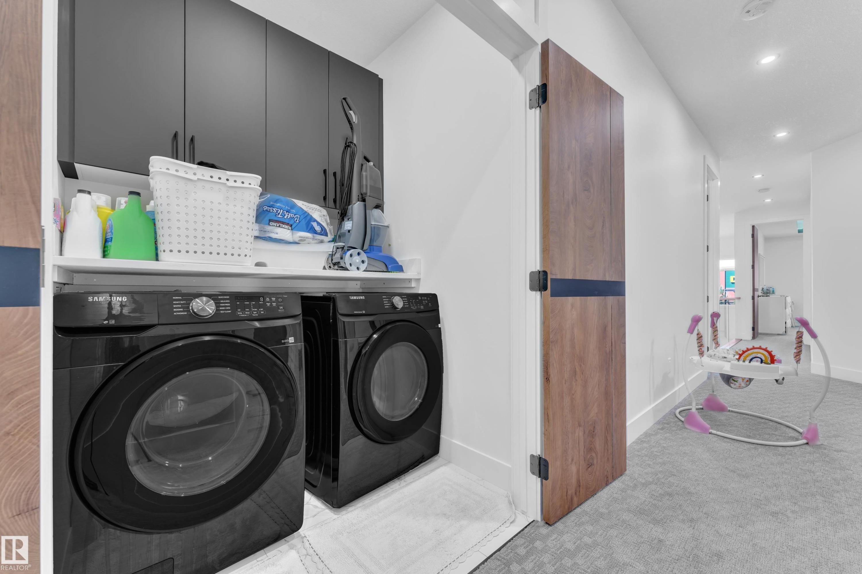 Dedicated laundry area featuring dark cabinetry, a built-in counter, and modern appliances - 16816 49 Street, Edmonton, AB