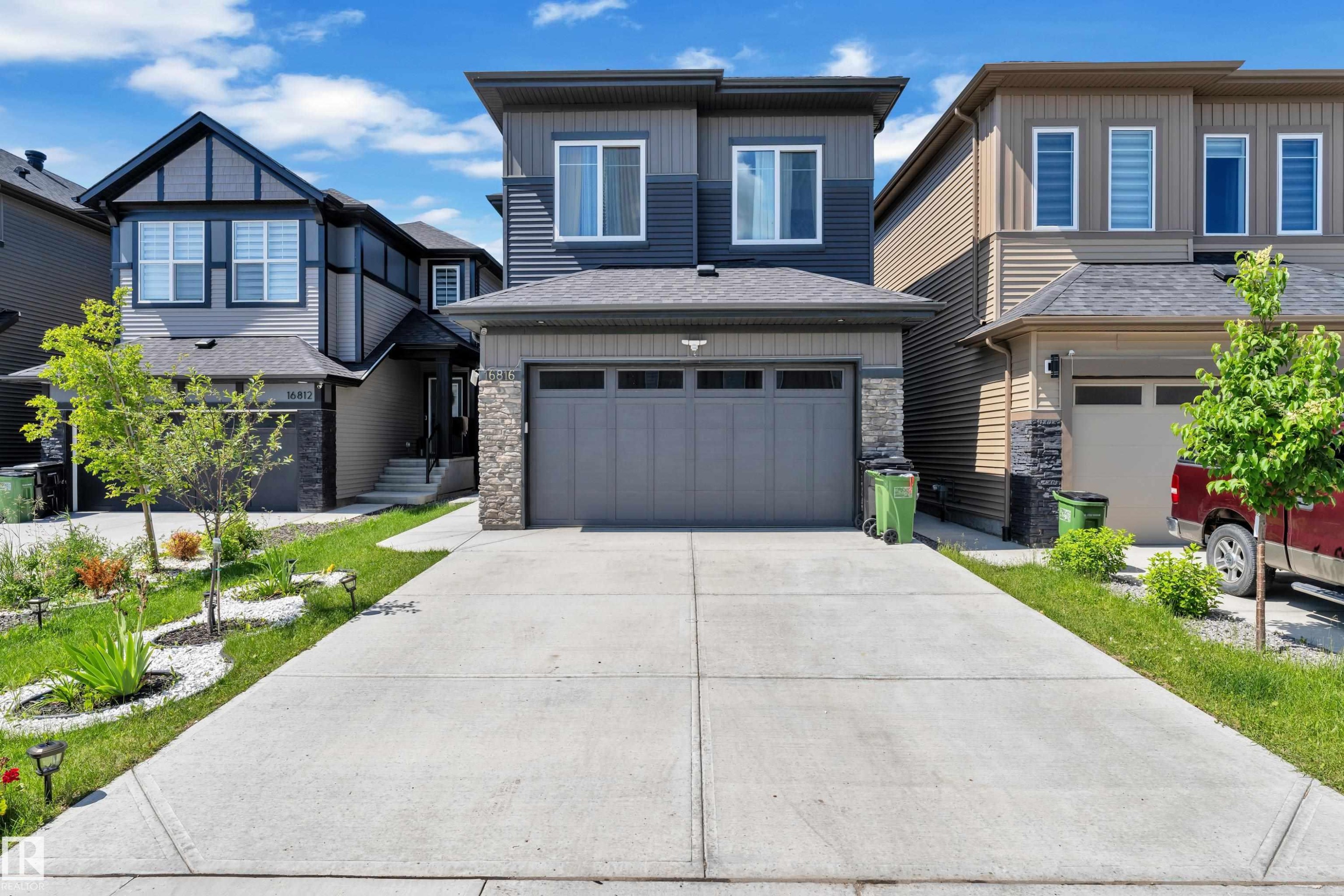 Contemporary two-story exterior featuring a grey and dark blue façade with stone accents - 16816 49 Street, Edmonton, AB