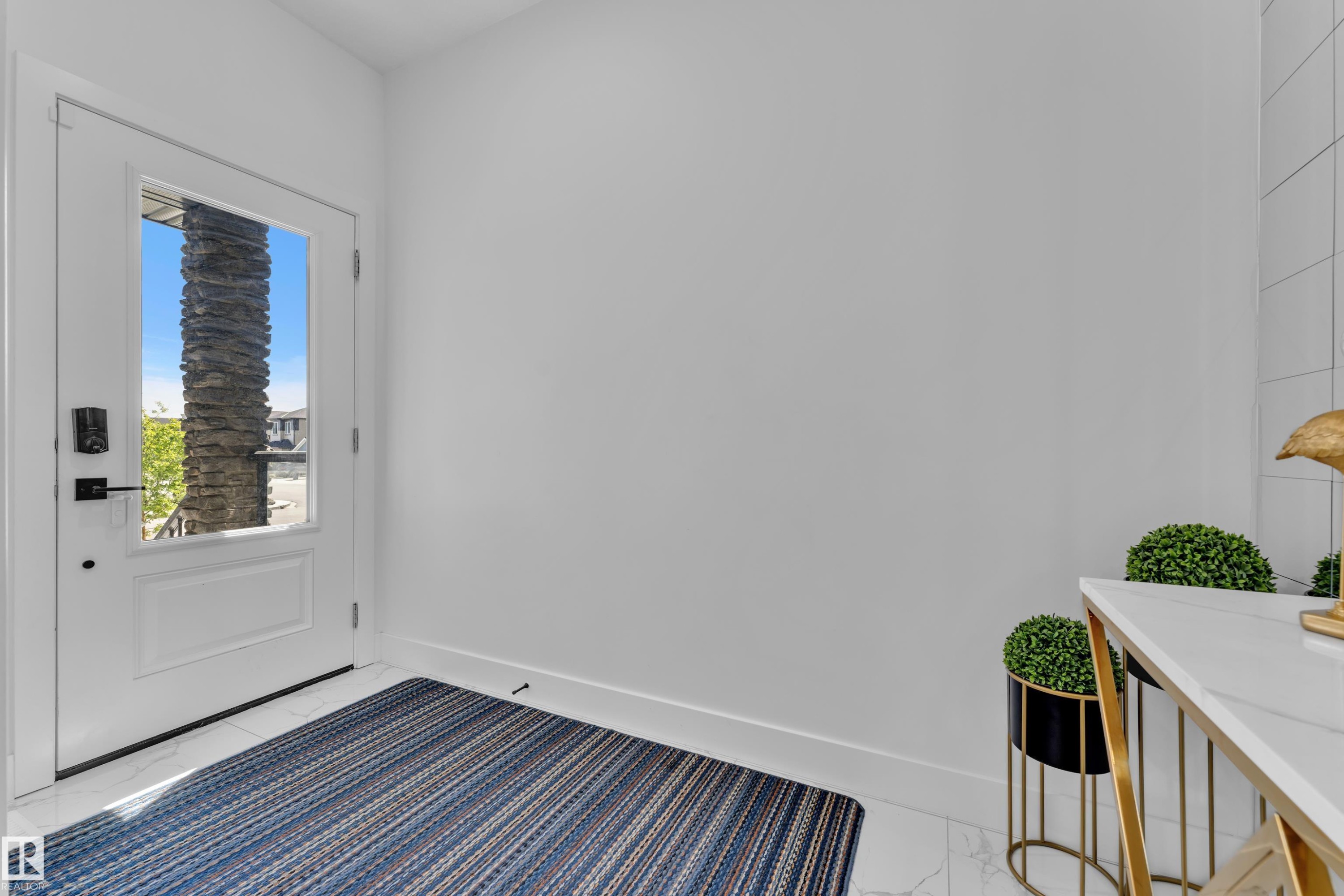Entryway featuring a white paneled door with a clear glass insert, matte black hardware, and white baseboards - 16816 49 Street, Edmonton, AB