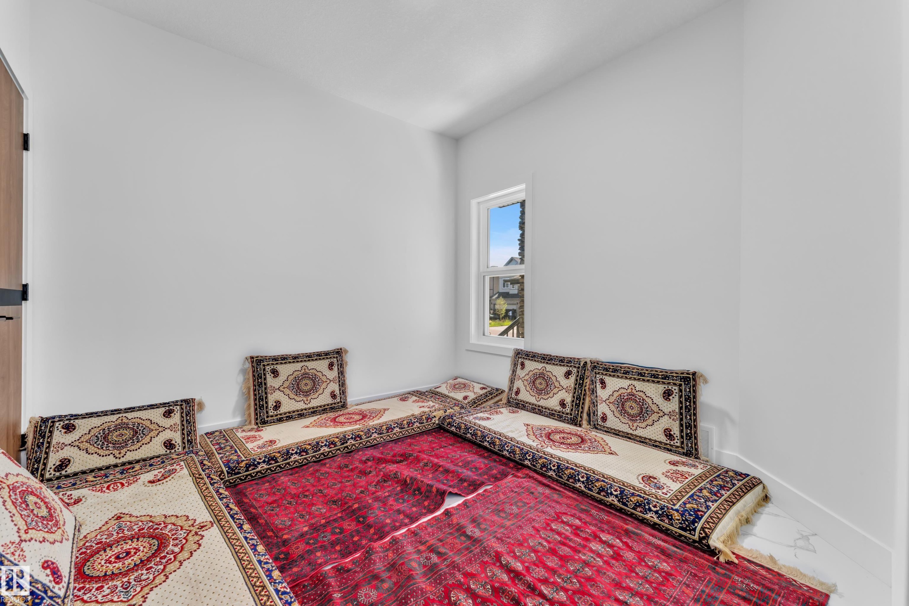 Bright room featuring a single window, white walls, and a wood-finish door with black hardware - 16816 49 Street, Edmonton, AB
