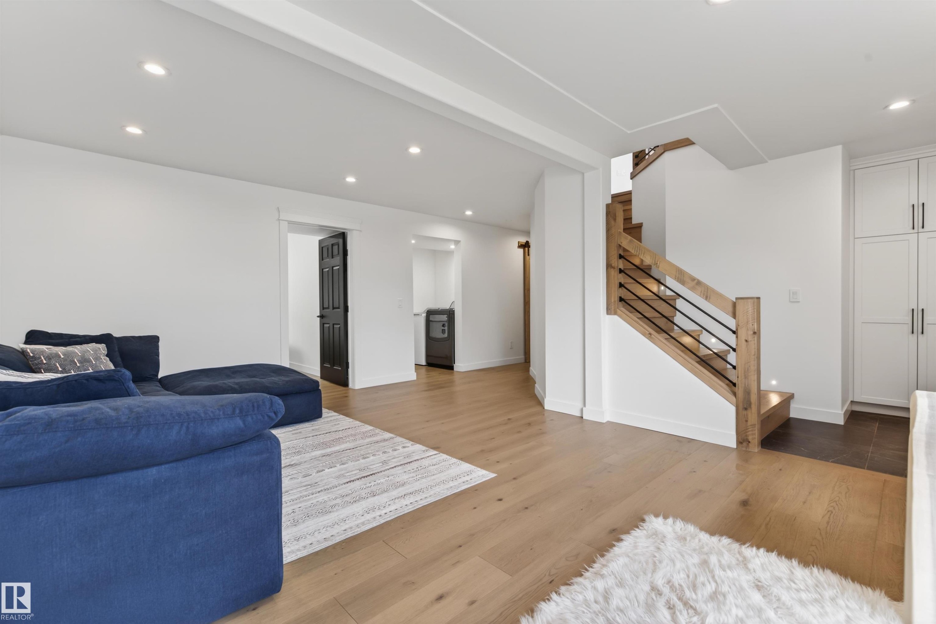 Modern staircase with light wood newel posts, handrail, and black metal balusters - 711 Beach Avenue, Cold Lake, AB - Indoor Photo Showing Living Room