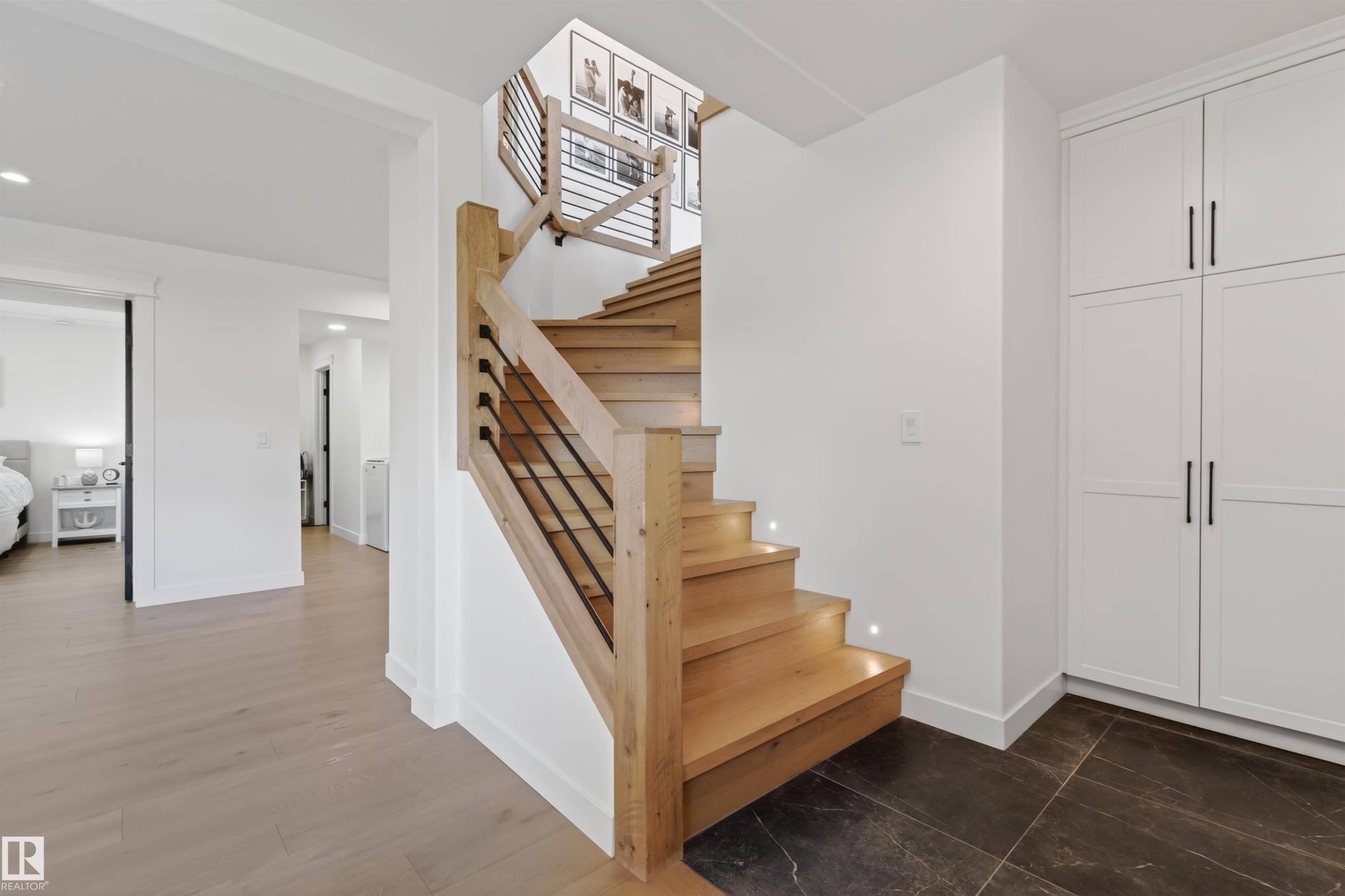 Modern staircase featuring wood treads with integrated lighting, a natural wood newel post, and minimalist black metal balusters - 711 Beach Avenue, Cold Lake, AB - Indoor Photo Showing Other Room