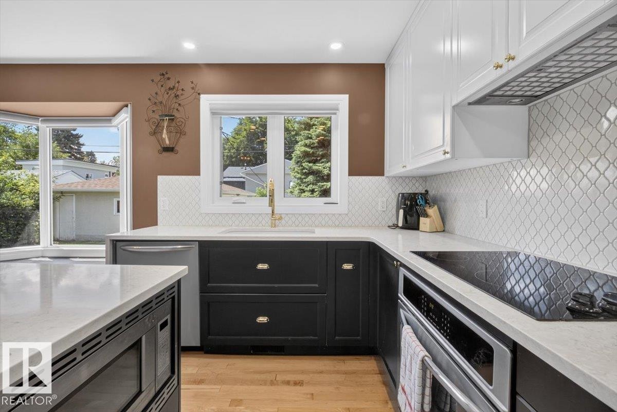 Modern kitchen featuring white shaker-style upper cabinetry and black lower cabinetry with brass hardware - 10736 48 Street Nw, Edmonton, AB - Indoor Photo Showing Kitchen With Upgraded Kitchen