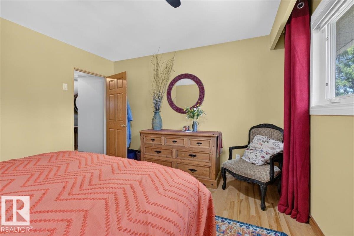 Bedroom featuring light wood-finish flooring, a window with white trim, and an open doorway revealing a closet - 10736 48 Street Nw, Edmonton, AB - Indoor Photo Showing Bedroom