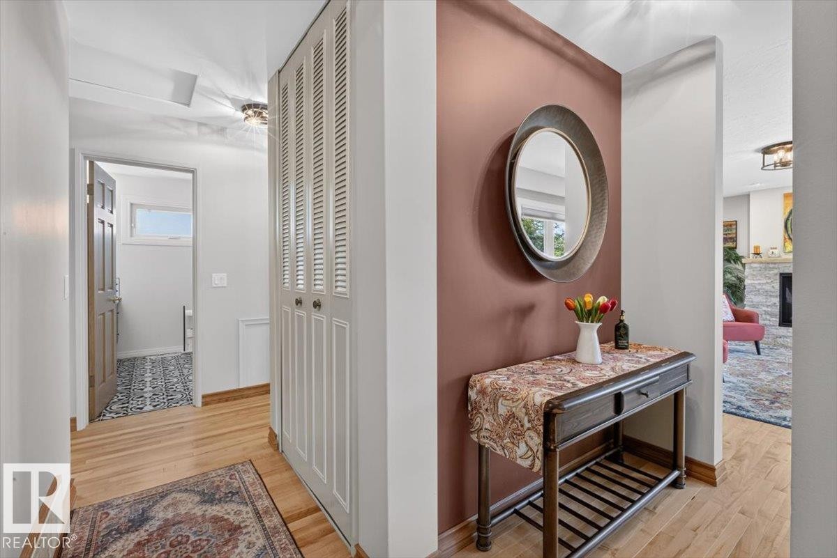 Hardwood-style flooring extends through the hallway, featuring a built-in louvered closet - 10736 48 Street Nw, Edmonton, AB - Indoor Photo Showing Other Room
