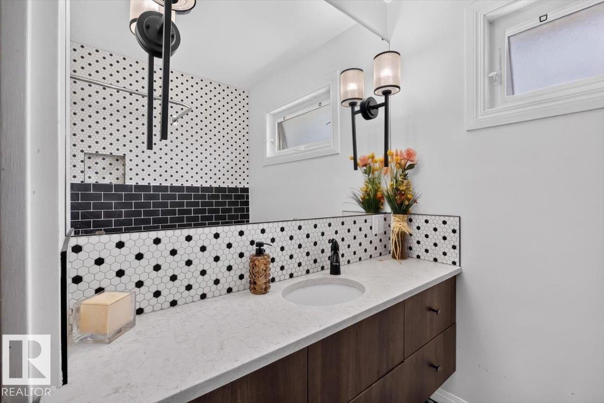 Bathroom featuring a wood-finish vanity with an integrated sink, quartz-finish countertop, and matte black faucet - 10736 48 Street Nw, Edmonton, AB - Indoor Photo Showing Bathroom