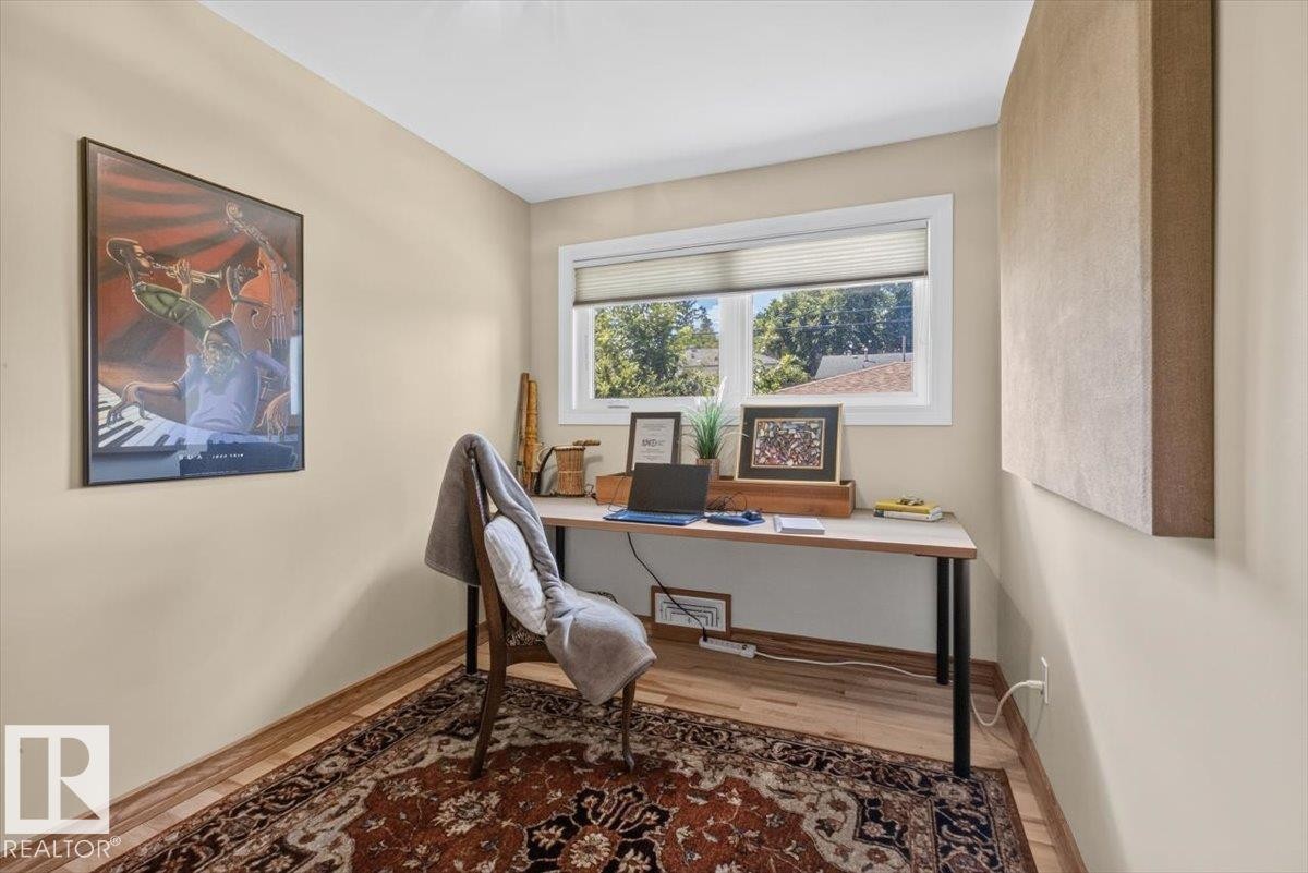 Versatile room featuring wood-finish flooring, a single window with blinds, and neutral-toned walls - 10736 48 Street Nw, Edmonton, AB - Indoor Photo Showing Office