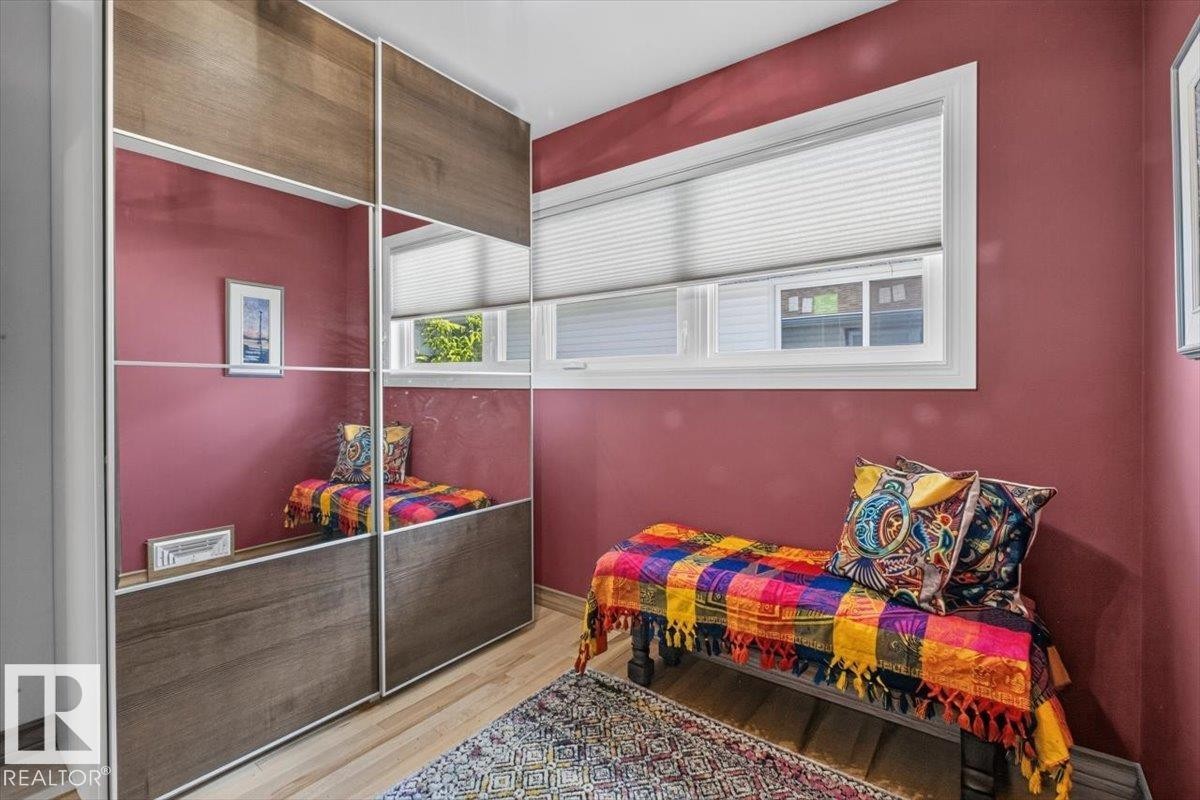 Built-in wardrobe with wood-finish and mirrored panels, light wood-finish flooring, white window trim, and a window with privacy blinds - 10736 48 Street Nw, Edmonton, AB - Indoor
