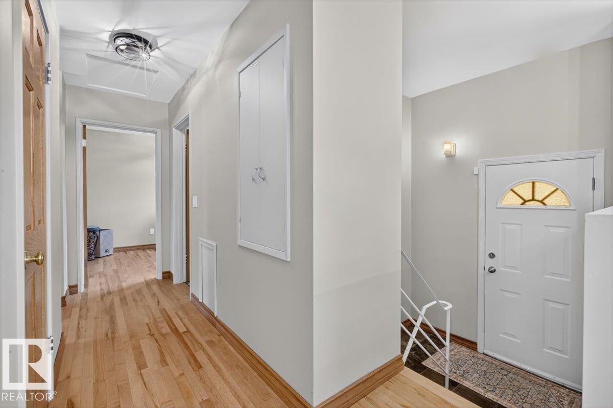 Entryway with light wood-finish flooring, white paneled door with arched transom, and recessed wall paneling - 10736 48 Street Nw, Edmonton, AB - Indoor Photo Showing Other Room