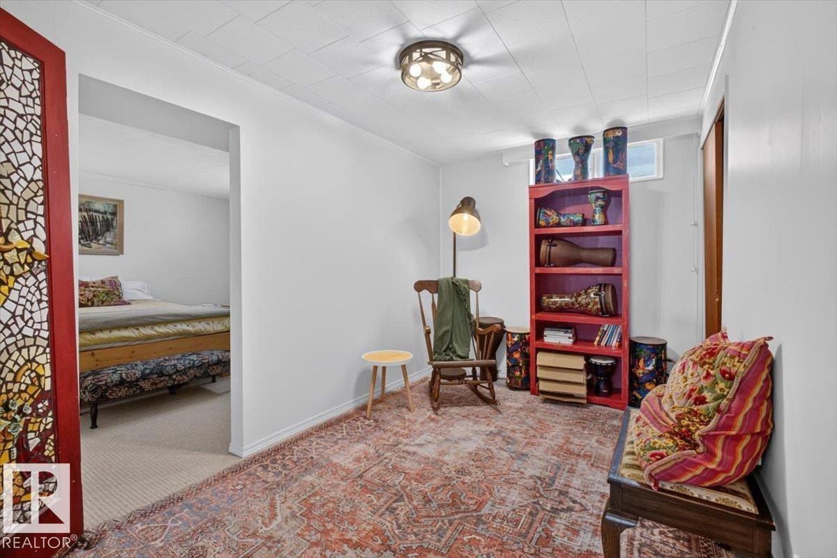 Open concept room featuring a decorative stained-glass door, overhead lighting, and an archway leading to an additional space - 10736 48 Street Nw, Edmonton, AB - Indoor
