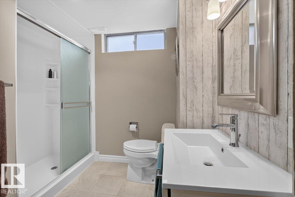 Full bathroom featuring a white vanity with an integrated rectangular sink, a chrome faucet, and a large mirrored cabinet - 10736 48 Street Nw, Edmonton, AB - Indoor Photo Showing Bathroom