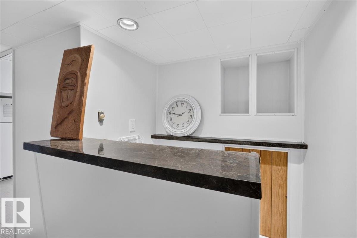 Dark-toned countertop with a smooth surface, white walls, recessed ceiling lighting, and built-in wall shelving - 10736 48 Street Nw, Edmonton, AB - Indoor Photo Showing Other Room
