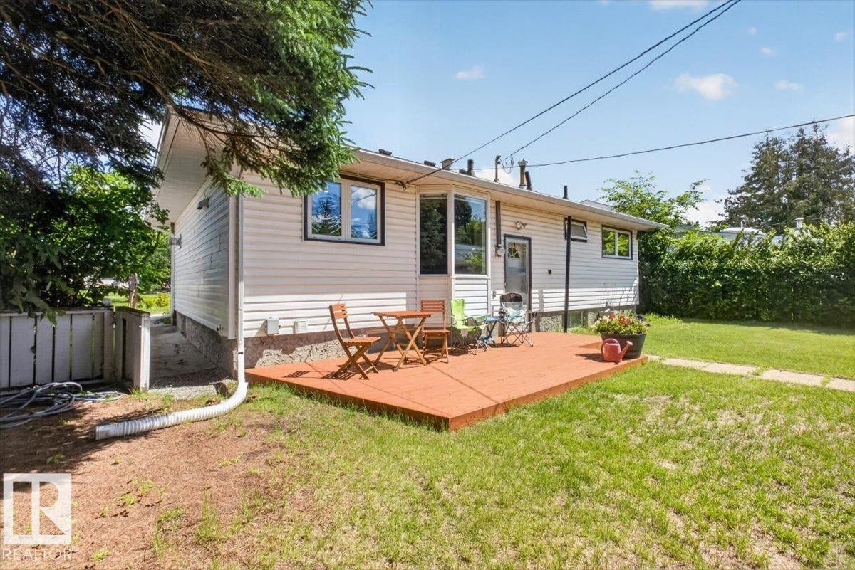 Exterior featuring white siding, a prominent wood-tone deck, and a bay window - 10736 48 Street Nw, Edmonton, AB - Outdoor