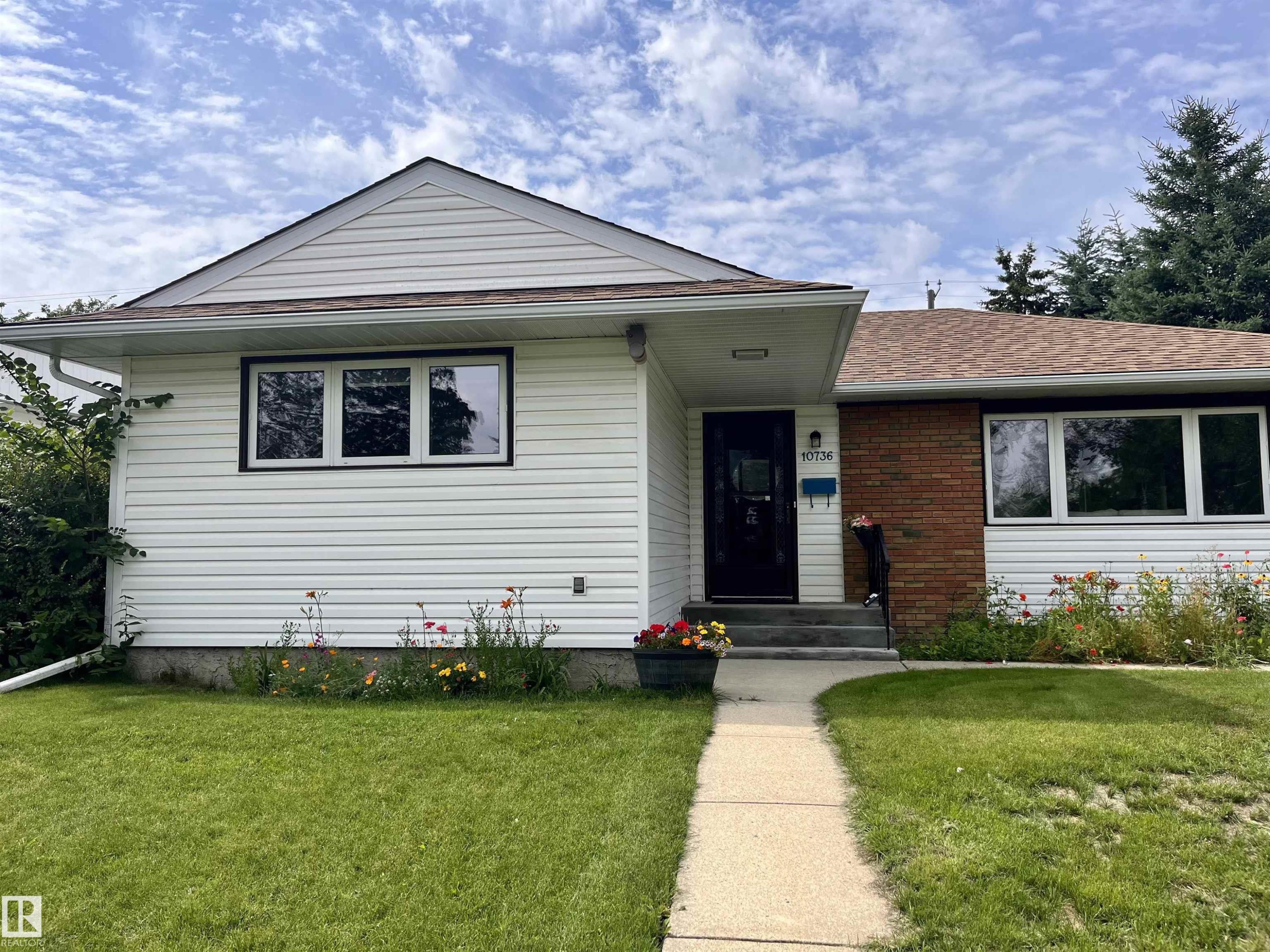 White siding exterior with brick accents, asphalt shingle roof, and a concrete walk-up leading to the entrance - 10736 48 Street Nw, Edmonton, AB - Outdoor