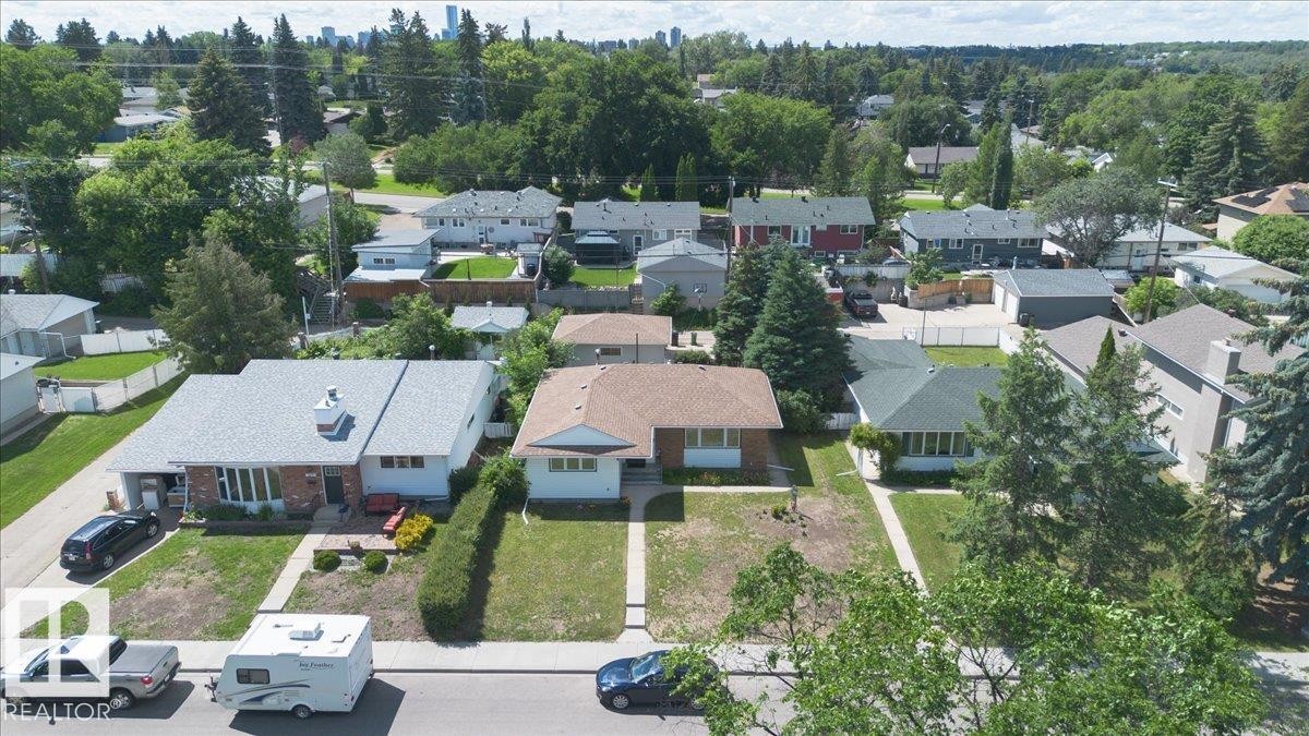 Single-story residence featuring a light gray shingle roof, brick and white siding exterior, and a manicured front lawn - 10736 48 Street Nw, Edmonton, AB - Outdoor With View