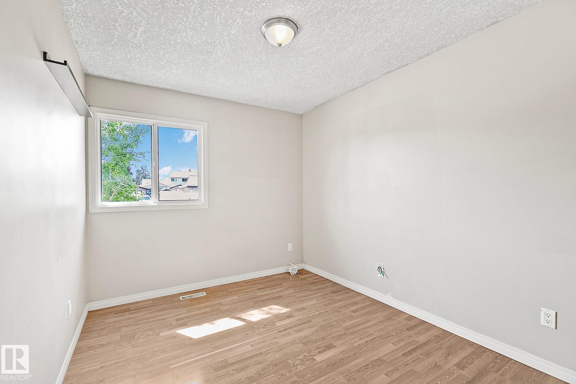 Room featuring wood-finish flooring, white baseboards, and neutral wall paint - 17059 98 Street, Edmonton, AB - Indoor Photo Showing Other Room