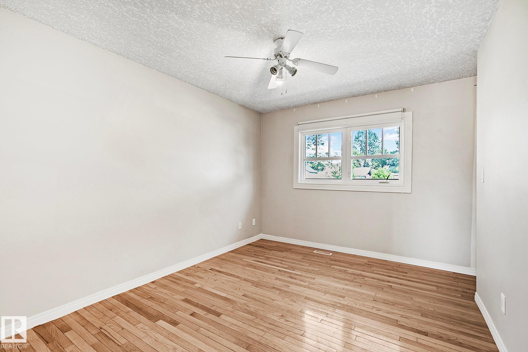Room featuring wood flooring, neutral wall paint, a white window frame, and a ceiling fan with integrated lighting - 17059 98 Street, Edmonton, AB - Indoor Photo Showing Other Room