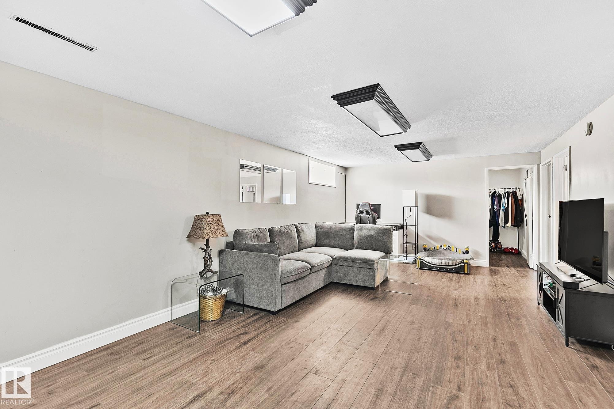 Spacious living area featuring wood-finish flooring, recessed lighting, and crisp white baseboards - 17059 98 Street, Edmonton, AB - Indoor