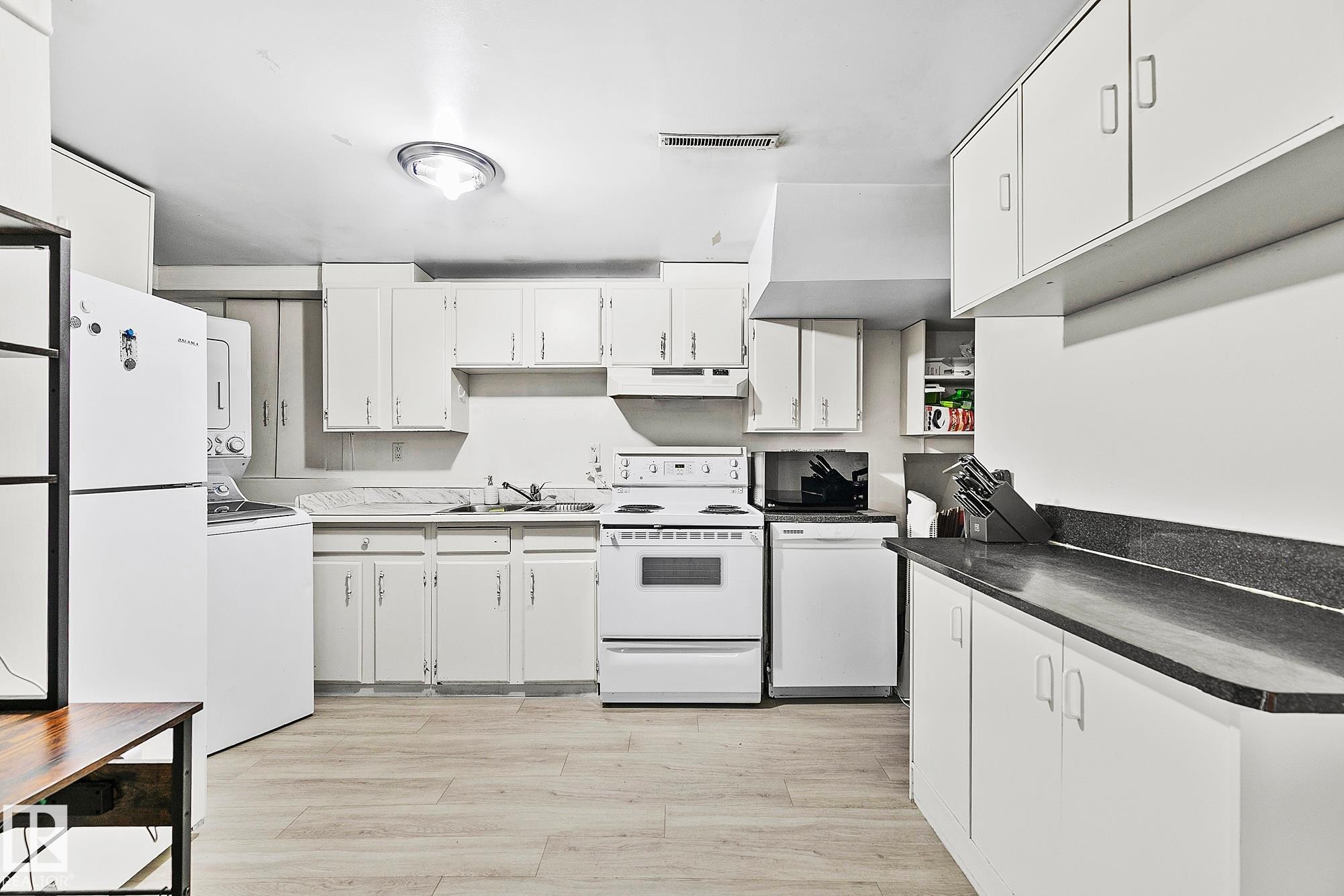 Kitchen featuring wood-finish flooring, white cabinetry, and dark countertops - 17059 98 Street, Edmonton, AB - Indoor Photo Showing Kitchen