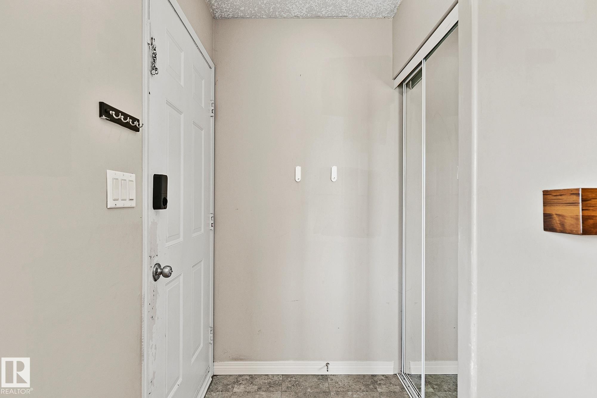 Entryway featuring a paneled door with smart lock hardware, a sliding mirrored closet door, and gray-toned flooring - 17059 98 Street, Edmonton, AB - Indoor Photo Showing Other Room