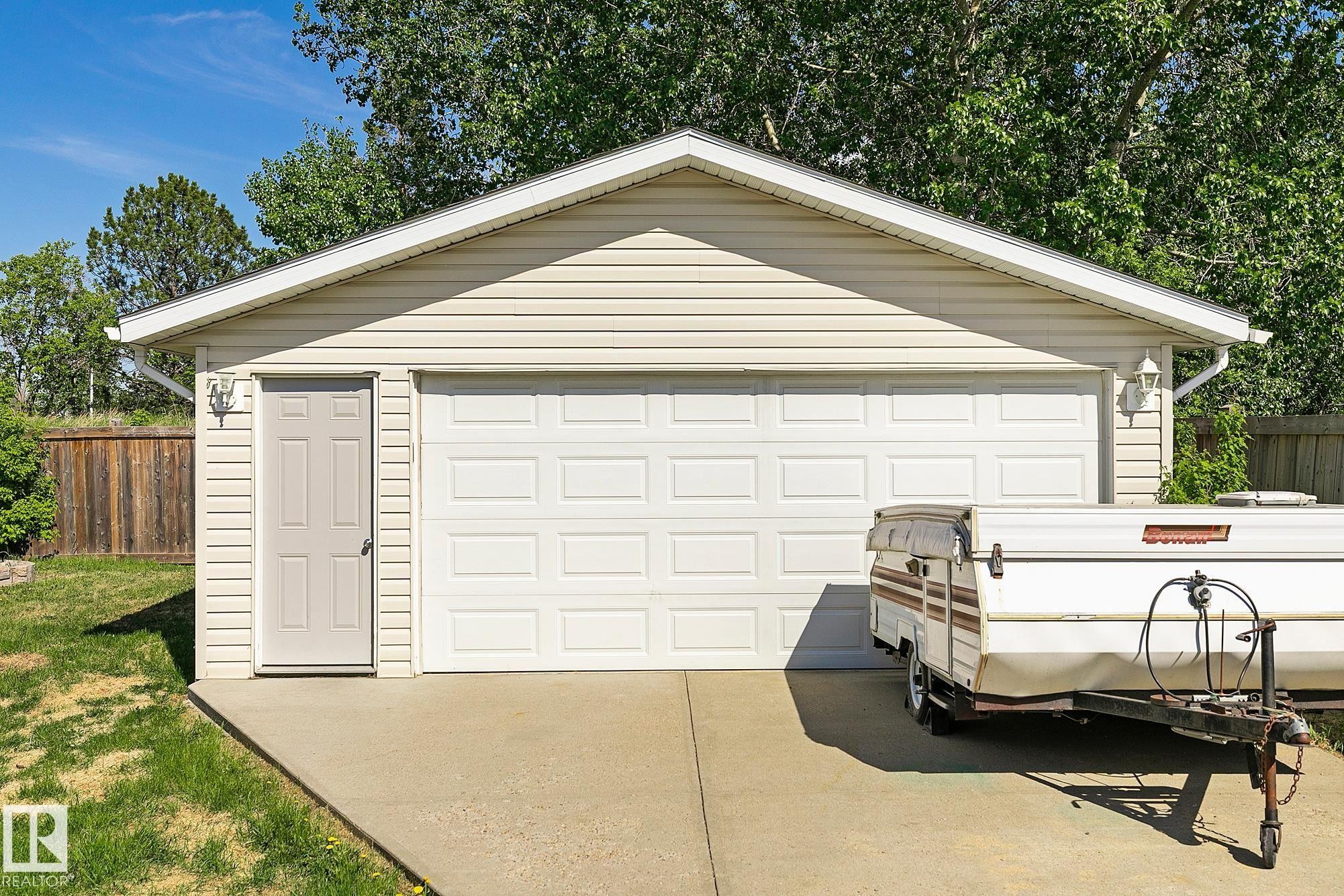 Detached two-car garage featuring panel-style doors and horizontal vinyl siding - 17059 98 Street, Edmonton, AB - Outdoor