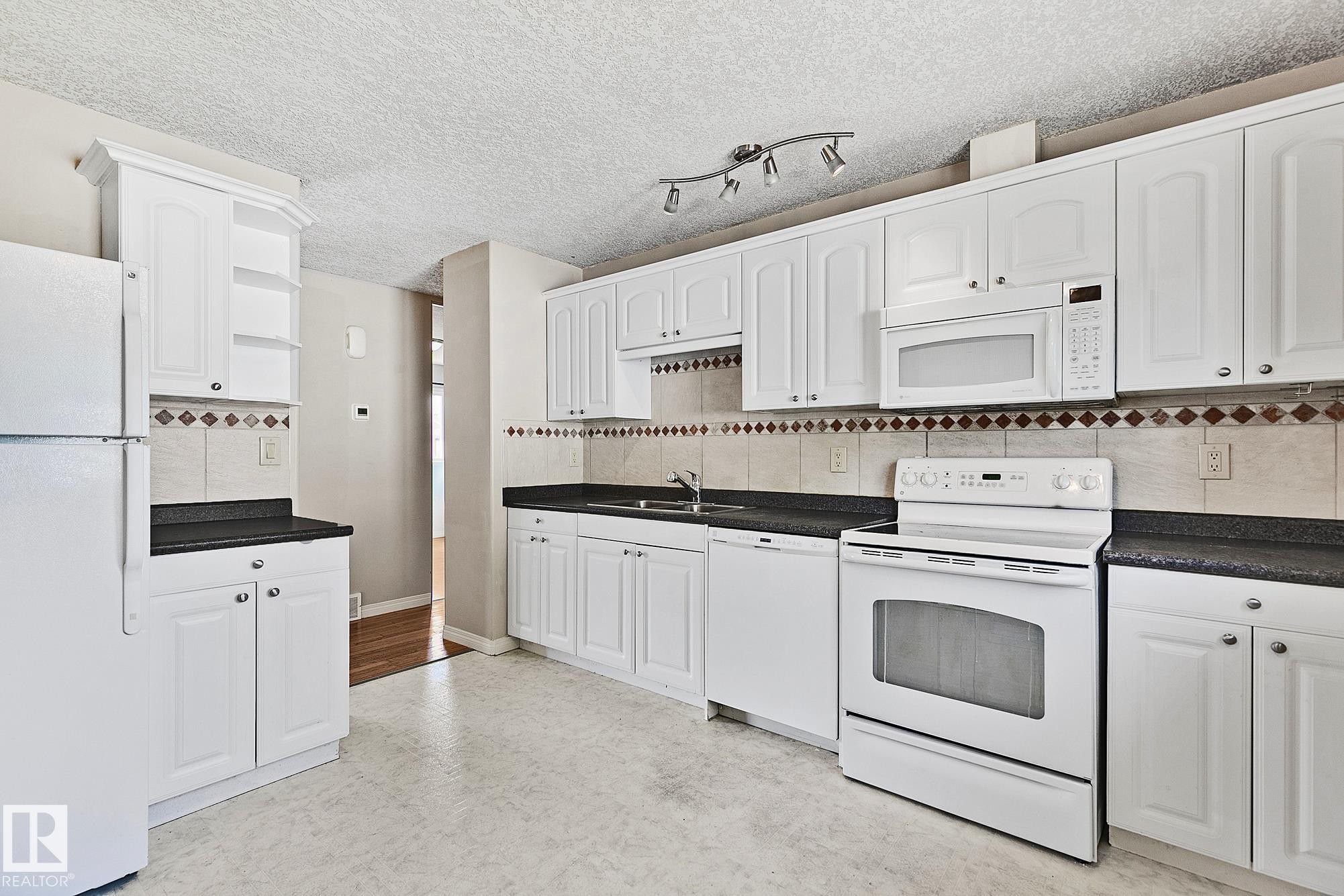 Kitchen featuring white cabinetry with matching appliances - 17059 98 Street, Edmonton, AB - Indoor Photo Showing Kitchen With Double Sink