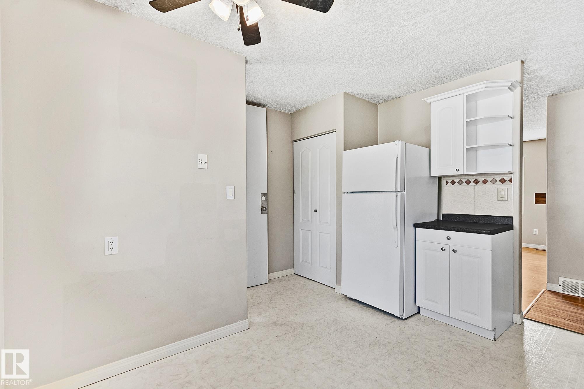 Kitchen area featuring white cabinetry, a black countertop, and a tiled backsplash - 17059 98 Street, Edmonton, AB - Indoor Photo Showing Other Room