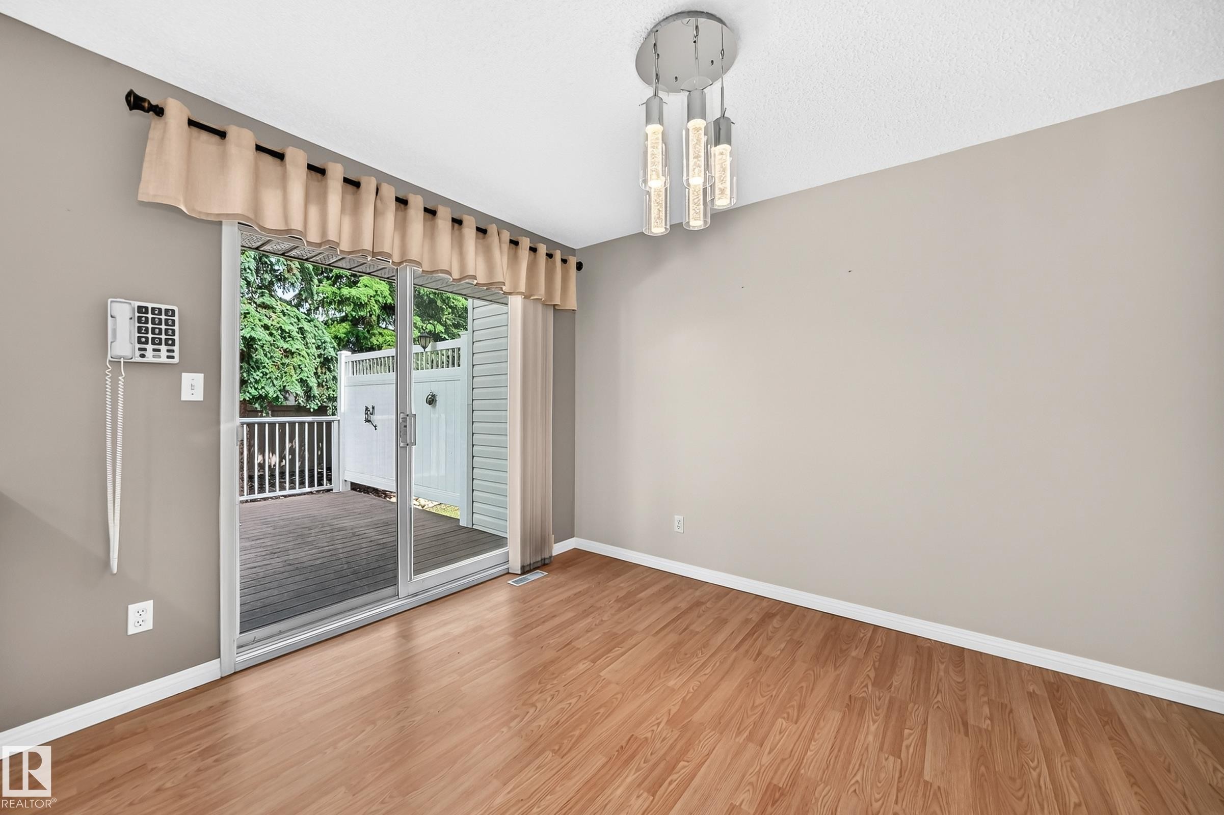 Hardwood-finish flooring extending to a sliding glass door leading to a deck - #51 9630 176 St Nw, Edmonton, AB - Indoor Photo Showing Other Room