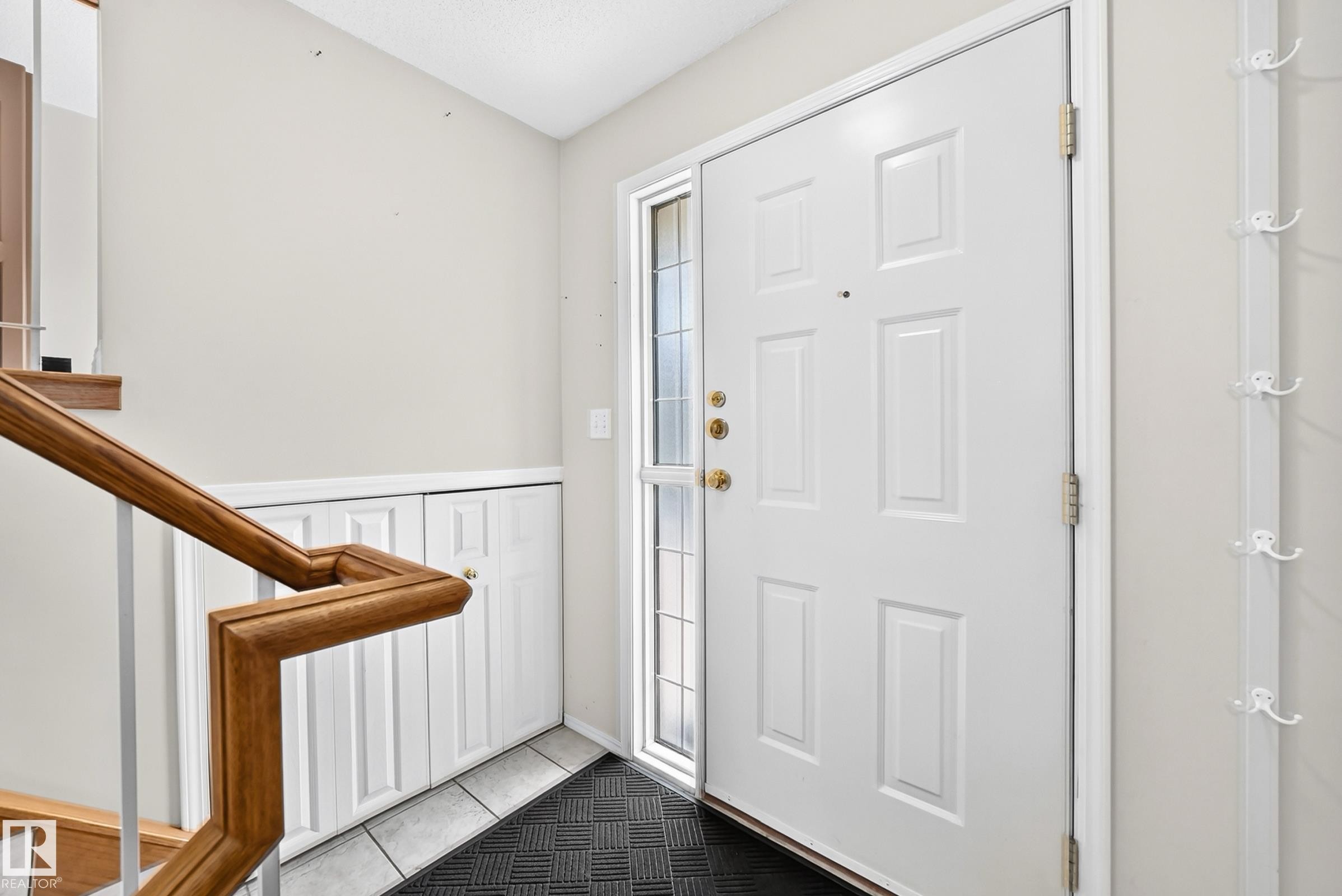 Entryway featuring a white paneled door with brass hardware, a full-length side-lite, and light-toned wall paint - #51 9630 176 St Nw, Edmonton, AB - Indoor Photo Showing Other Room