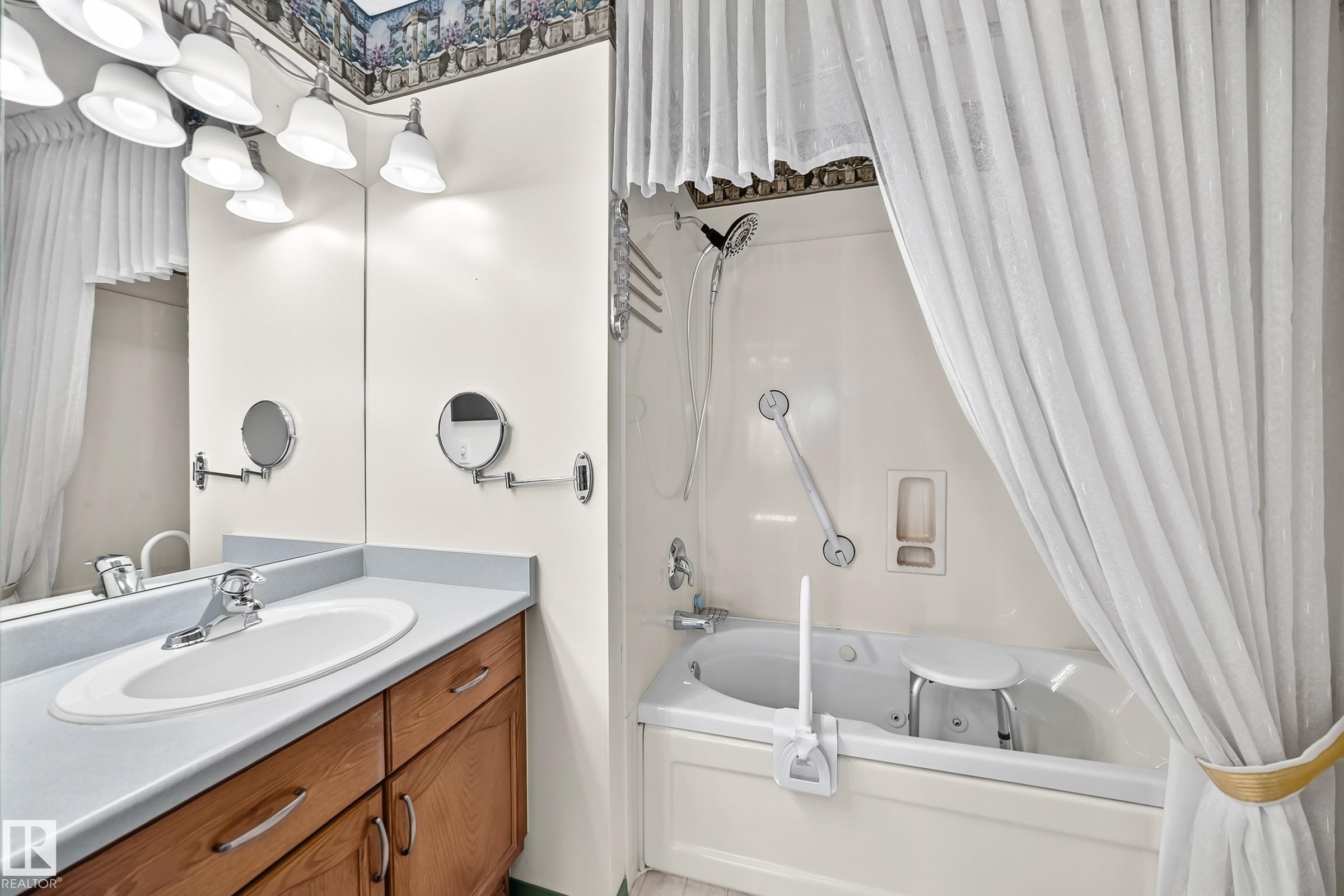 Bathroom vanity featuring a light-toned countertop with an integrated sink and wood-finish cabinetry - #51 9630 176 St Nw, Edmonton, AB - Indoor Photo Showing Bathroom