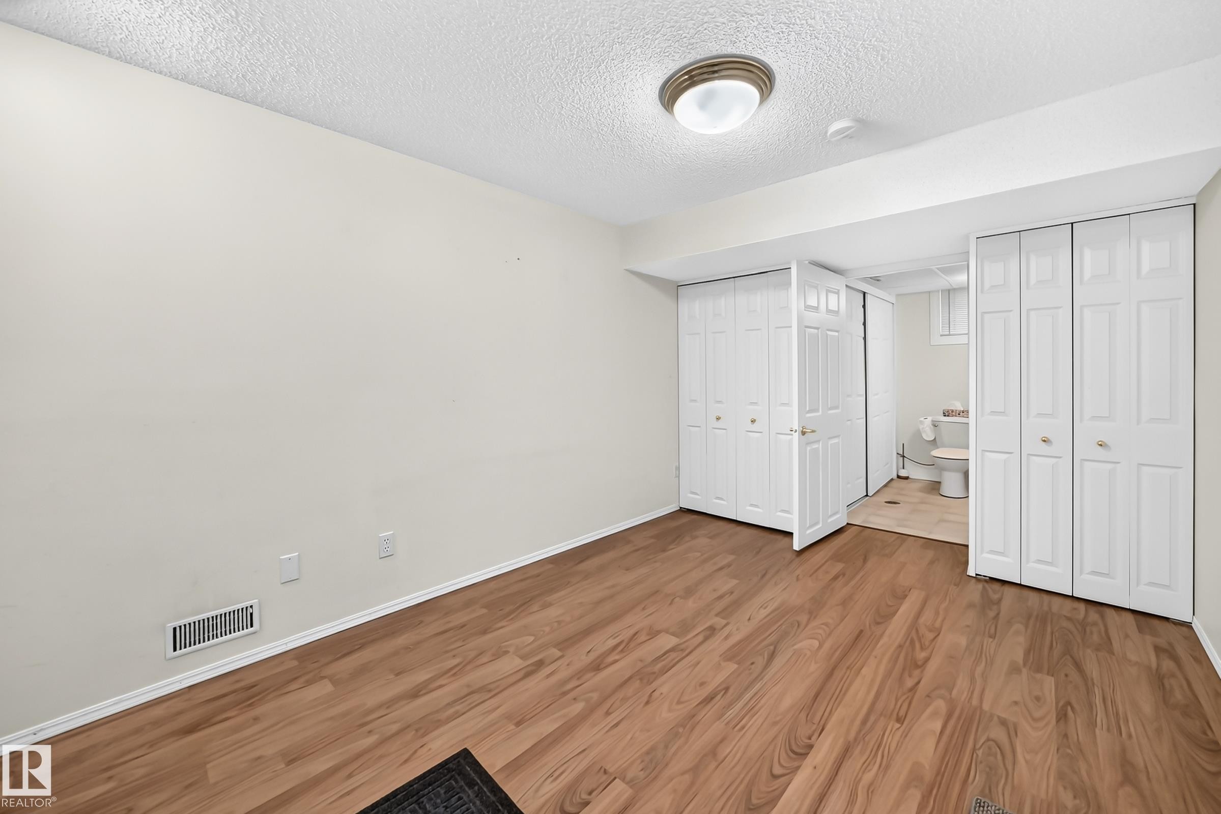 Room featuring wood-finish flooring, light-toned walls, and a ceiling-mounted light fixture - #51 9630 176 St Nw, Edmonton, AB - Indoor Photo Showing Other Room
