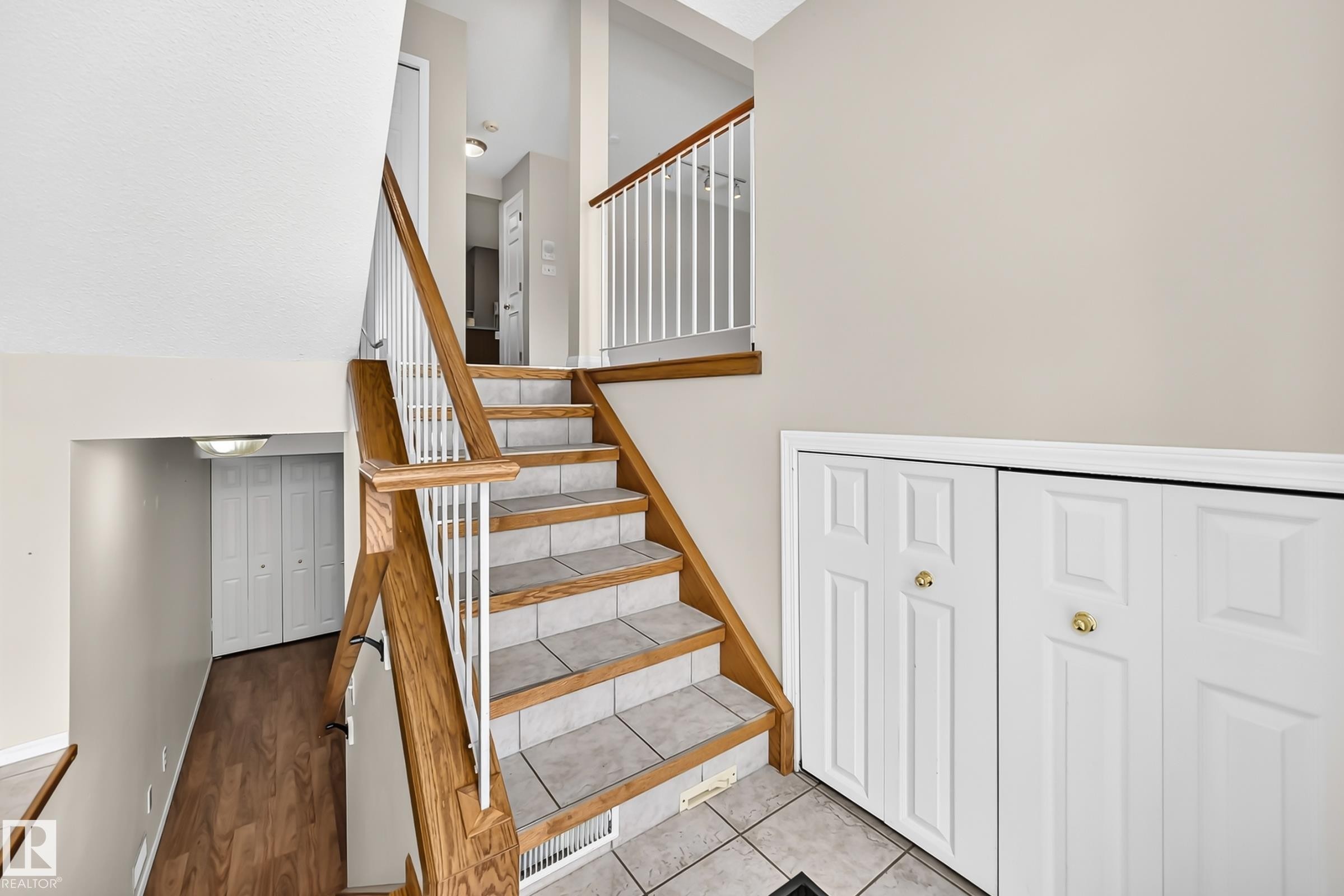 Multi-level interior featuring a staircase with wood-finish handrails and white balusters - #51 9630 176 St Nw, Edmonton, AB - Indoor Photo Showing Other Room
