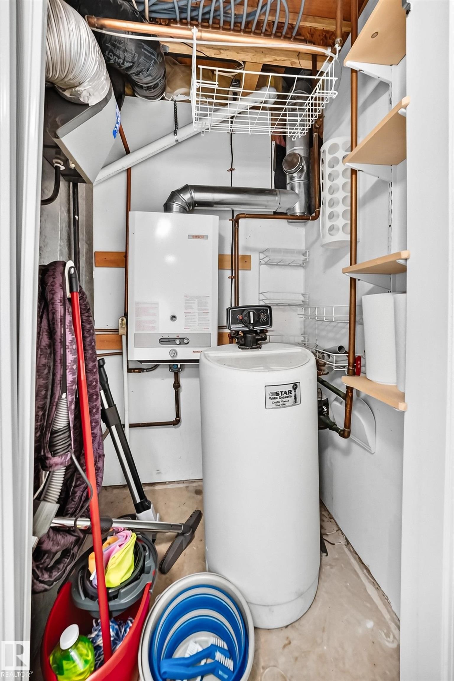 Utility closet featuring a wall-mounted tankless water heater, water softener system, copper piping, and open shelving - #51 9630 176 St Nw, Edmonton, AB - Indoor