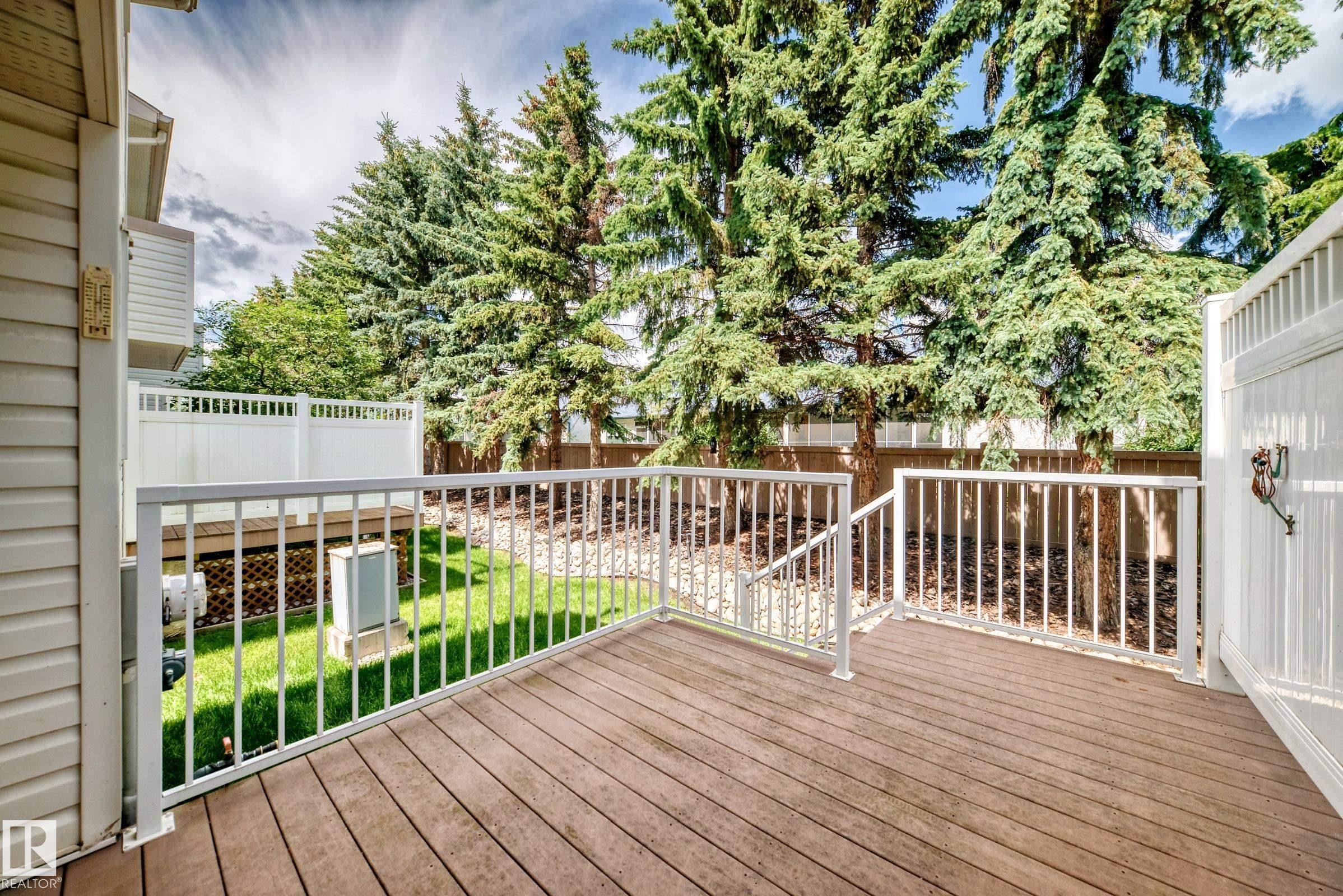 Spacious wood-finish deck with white railings, offering outdoor living space - #51 9630 176 St Nw, Edmonton, AB - Outdoor With Deck Patio Veranda With Exterior