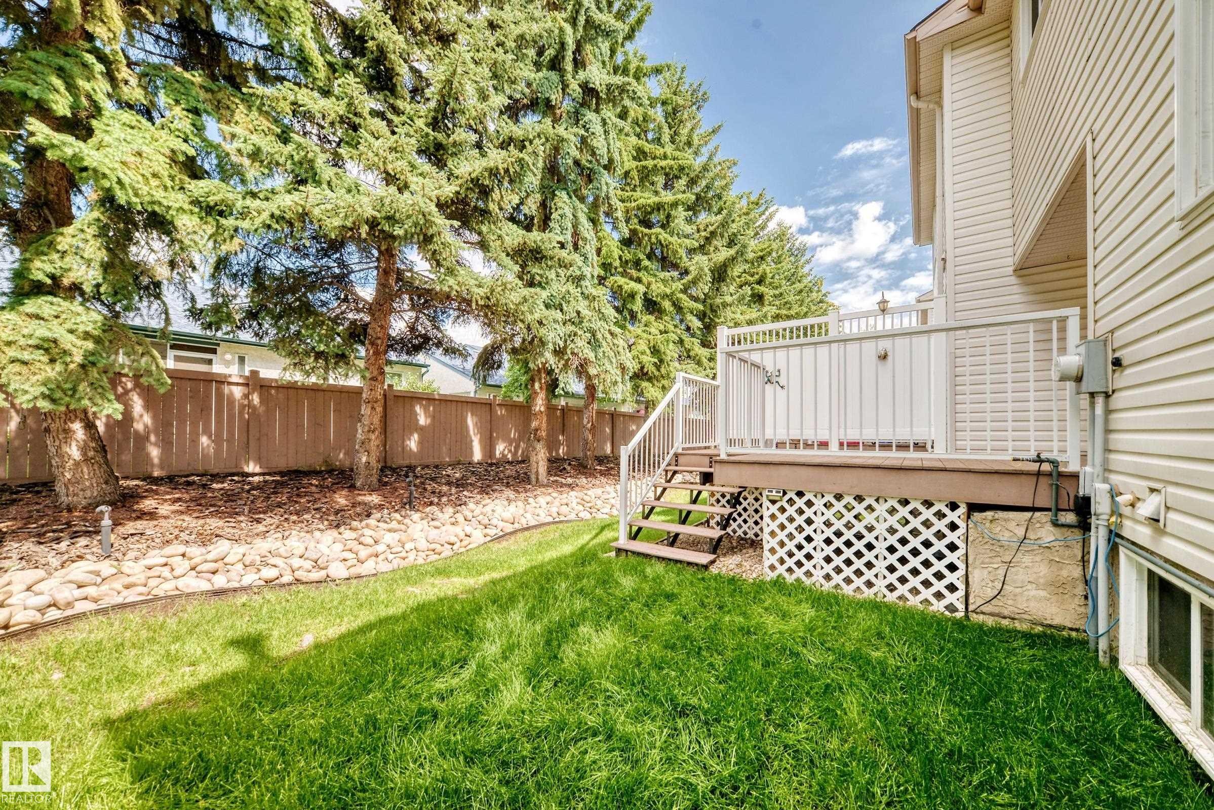 Rear exterior featuring a raised deck with white railings and steps to the lawn - #51 9630 176 St Nw, Edmonton, AB - Outdoor With Deck Patio Veranda