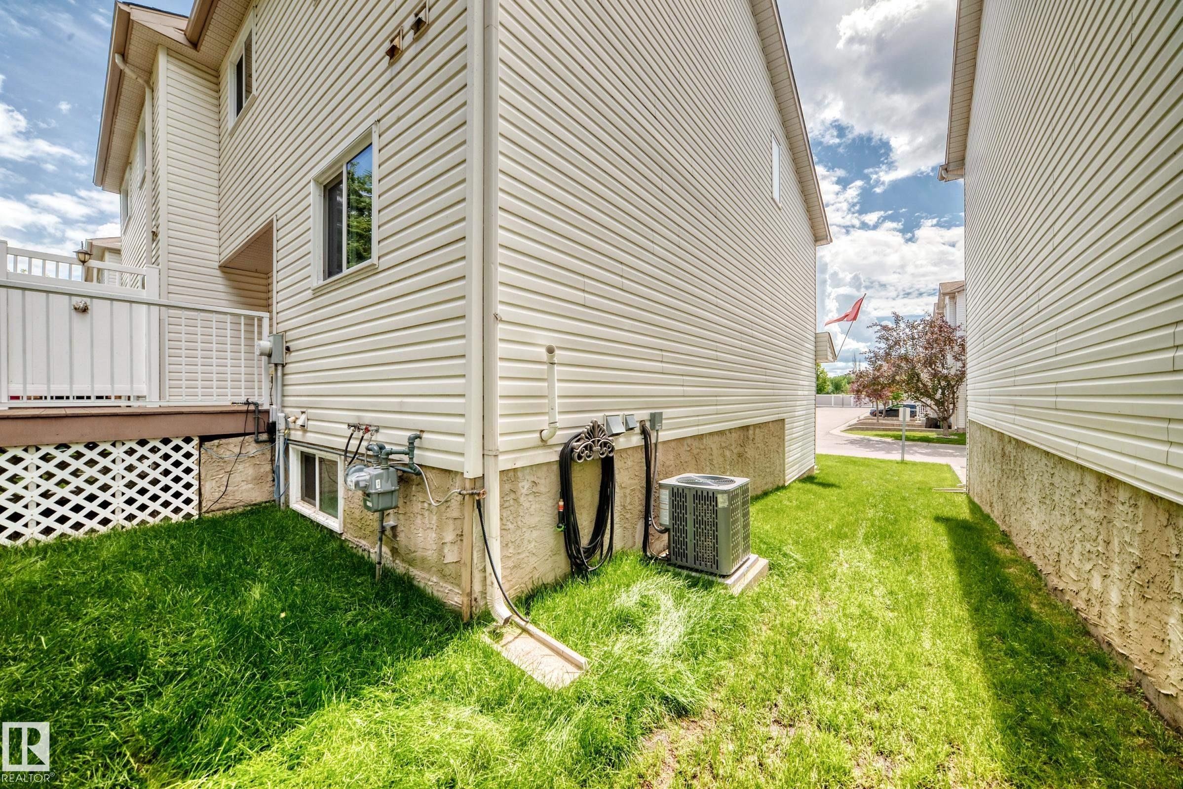 Cream-colored vinyl siding exterior with an elevated deck featuring white railings - #51 9630 176 St Nw, Edmonton, AB - Outdoor With Deck Patio Veranda With Exterior