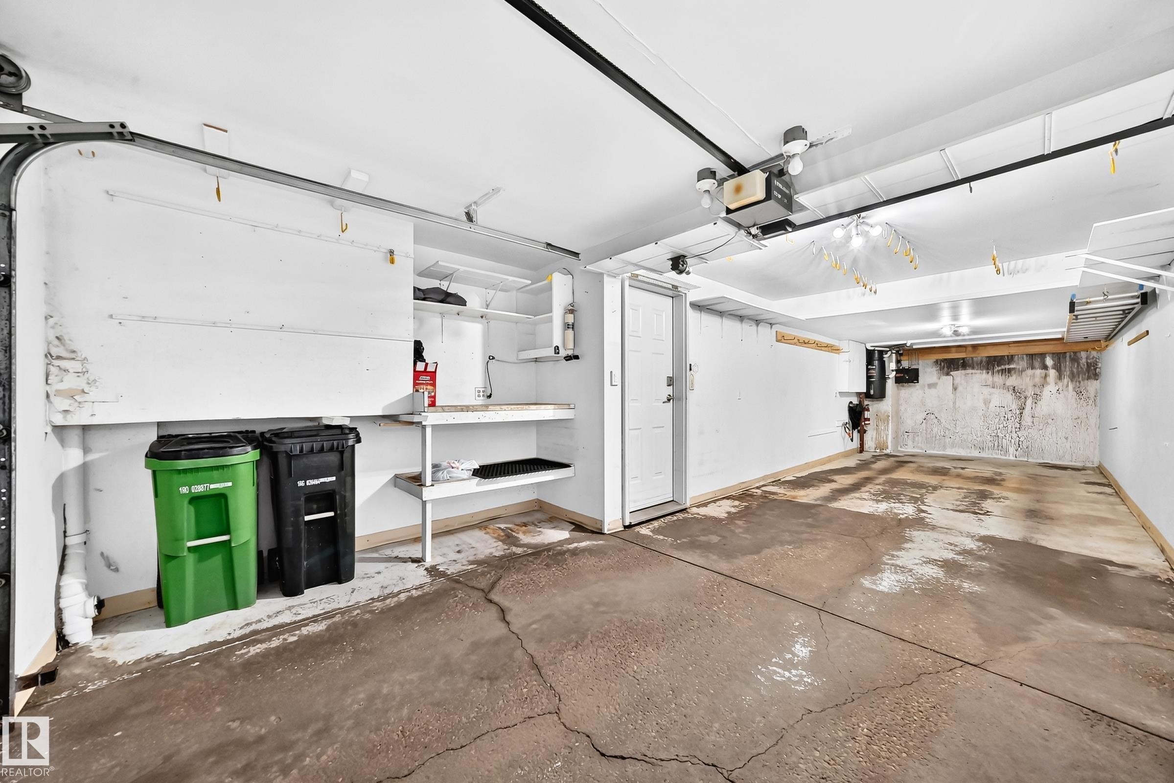 Spacious two-car garage with a concrete floor and white painted walls - #51 9630 176 St Nw, Edmonton, AB - Indoor Photo Showing Garage