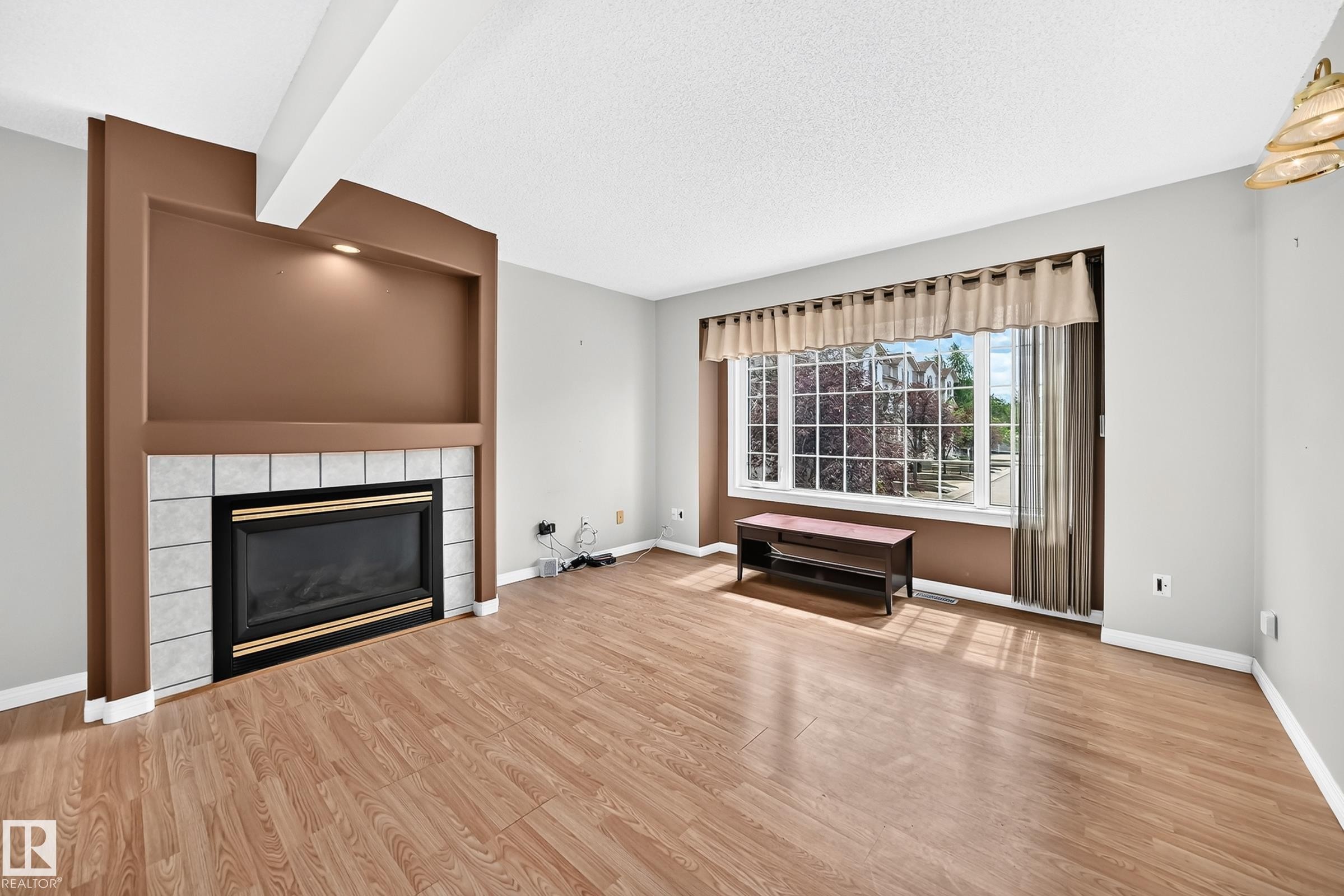 Living area featuring a tiled fireplace with an integrated display niche and recessed lighting - #51 9630 176 St Nw, Edmonton, AB - Indoor Photo Showing Living Room With Fireplace