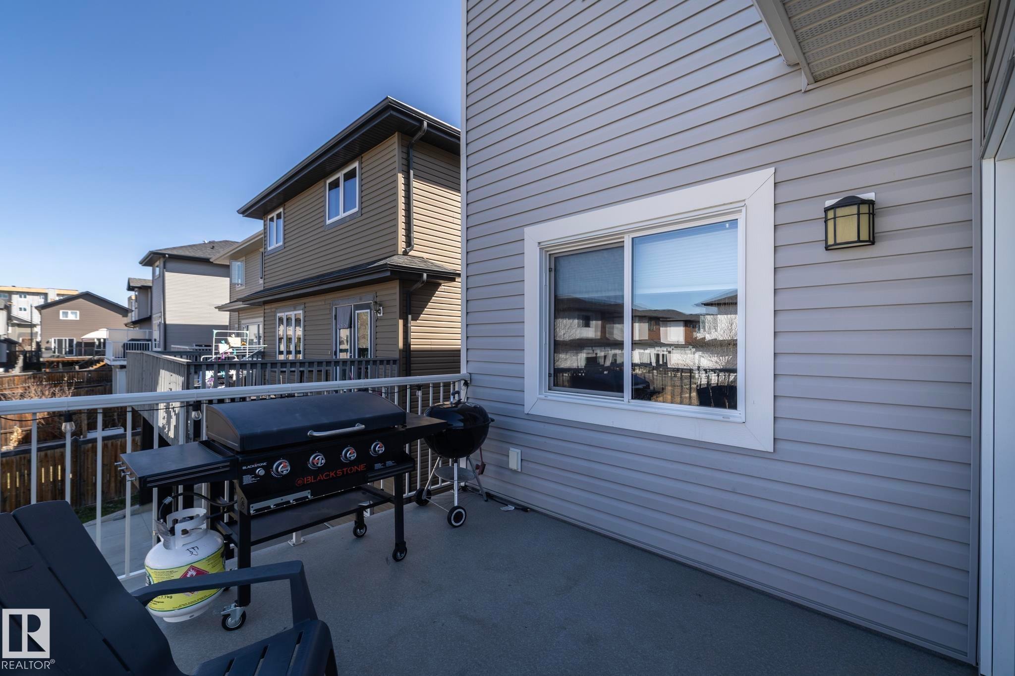 Outdoor balcony featuring gray siding and white trim around a window - 2016 Redtail Common, Edmonton, AB