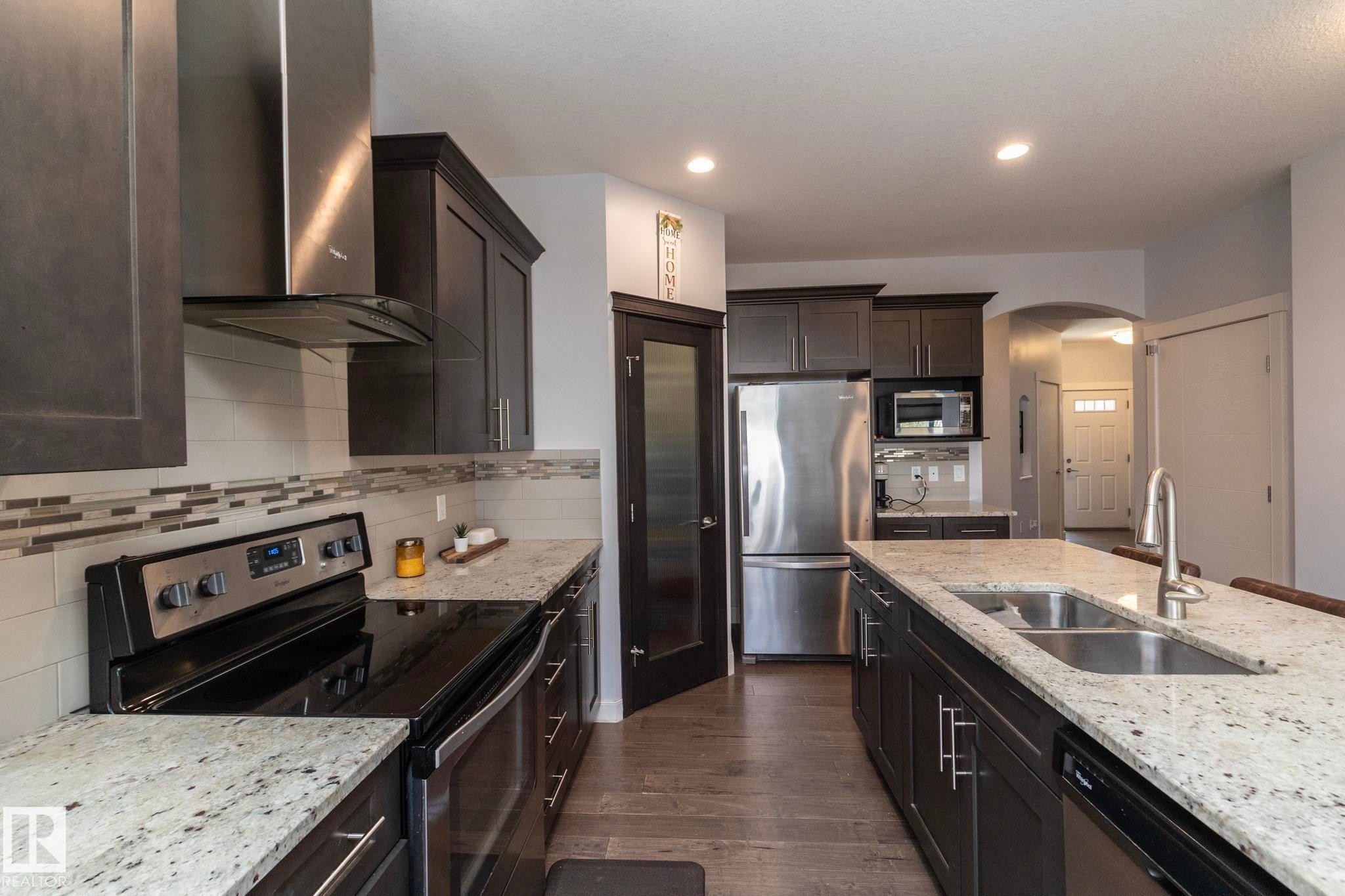 Modern kitchen featuring dark wood cabinetry and light-toned granite countertops - 2016 Redtail Common, Edmonton, AB