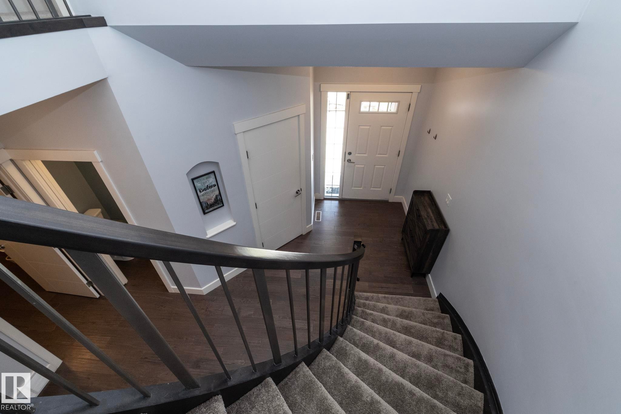 Curved carpeted staircase with dark wood-finish railing - 2016 Redtail Common, Edmonton, AB