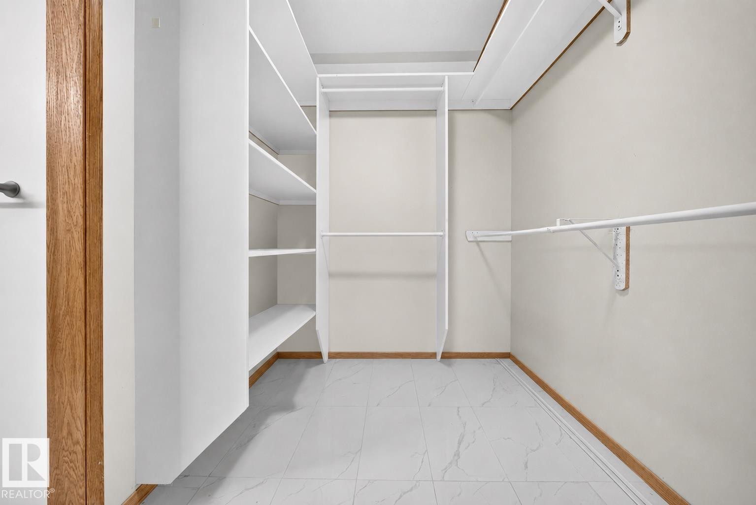 Walk-in closet featuring white built-in shelving, white hanging rods, light tone walls, and wood-finish trim - 6203 143 Street Nw, Edmonton, AB - Indoor With Storage