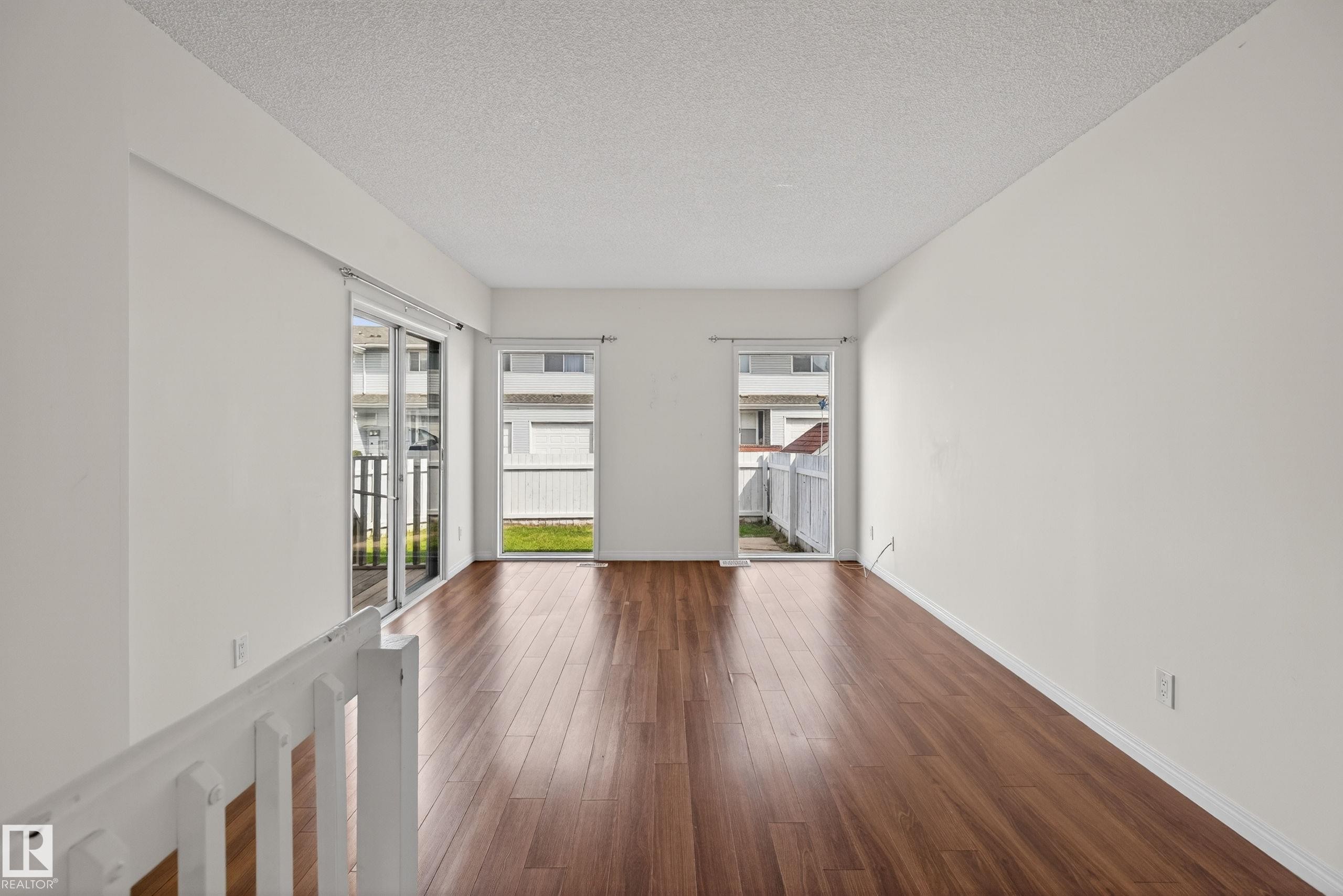Spacious room featuring wood-finish flooring, white walls, and a textured ceiling - 156 Lee Ridge Road, Edmonton, AB - Indoor Photo Showing Other Room