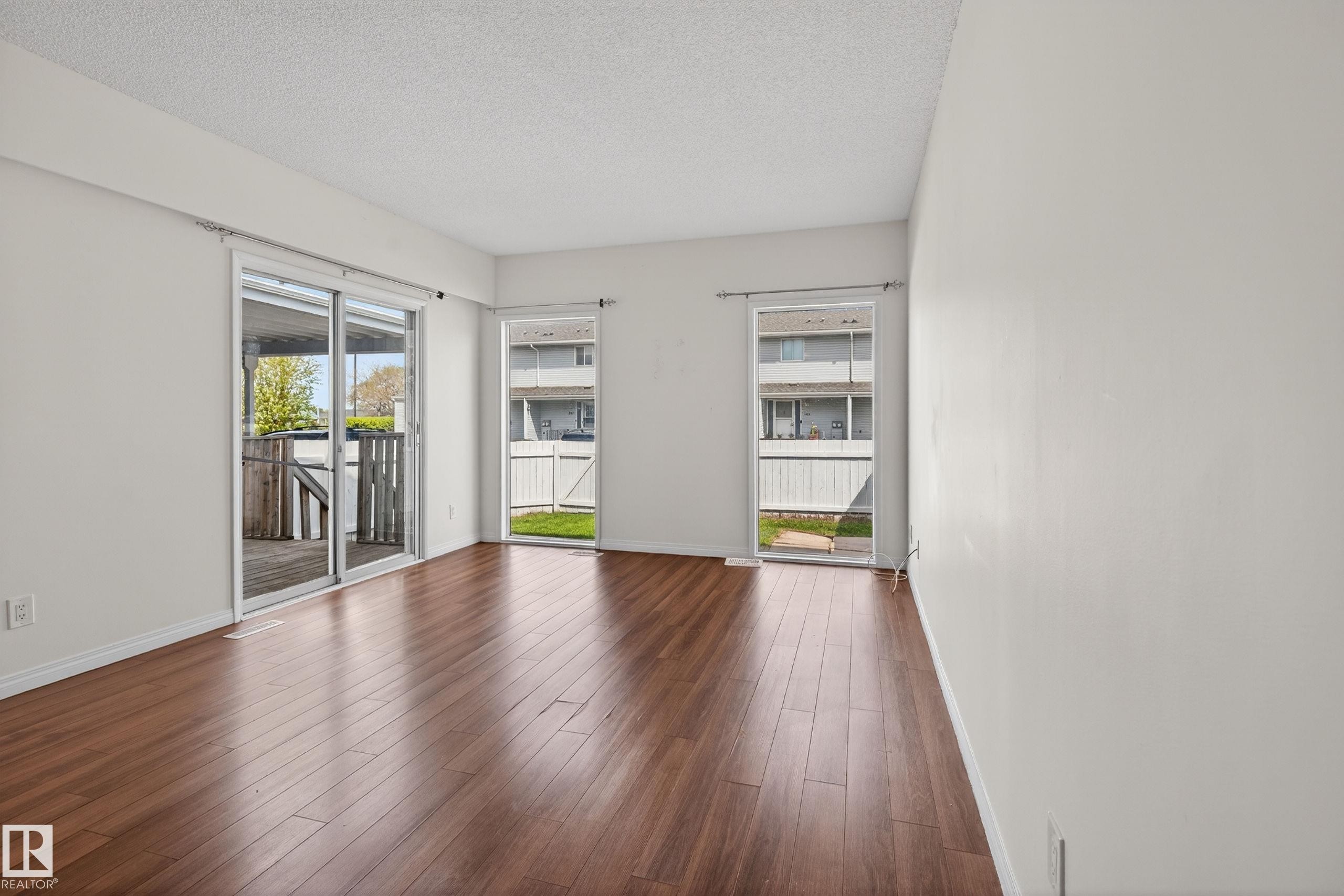 Spacious room with wood-finish flooring, white walls, and a textured white ceiling - 156 Lee Ridge Road, Edmonton, AB - Indoor