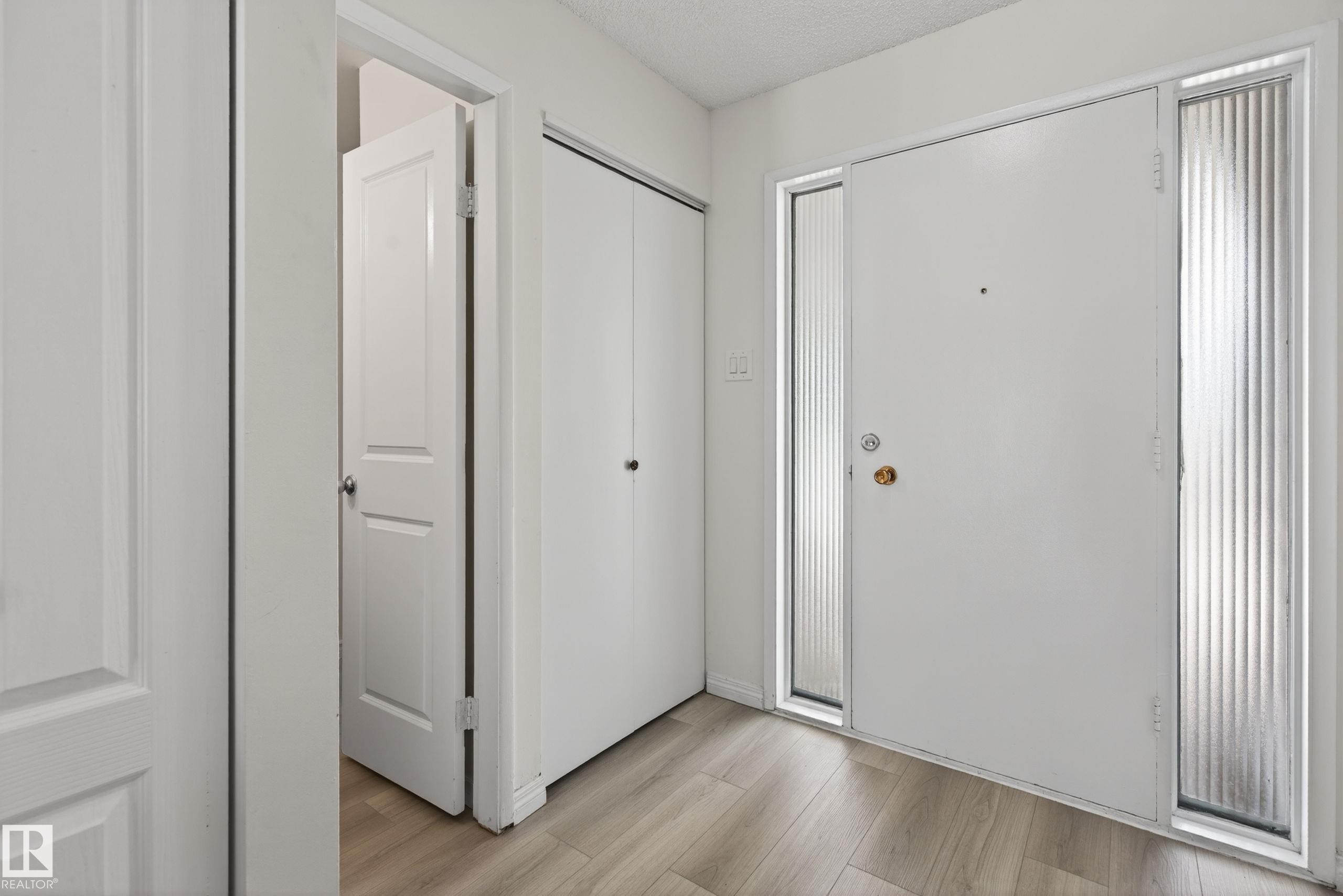 Entryway featuring a white main door with two fluted glass sidelights, complemented by wood-finish flooring - 156 Lee Ridge Road, Edmonton, AB - Indoor Photo Showing Other Room