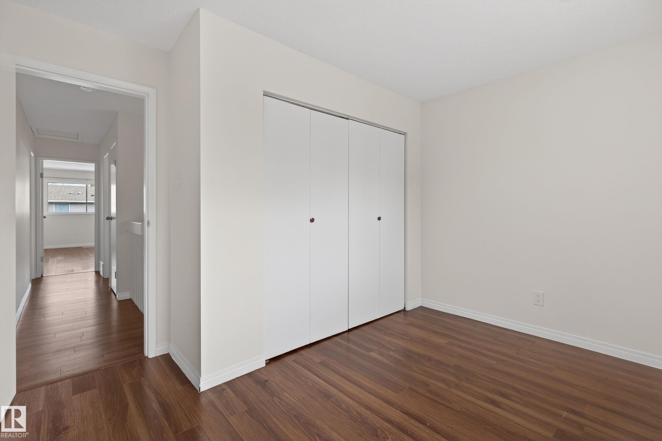 Room featuring wood-finish flooring, white walls, and a large bi-fold closet - 156 Lee Ridge Road, Edmonton, AB - Indoor Photo Showing Other Room