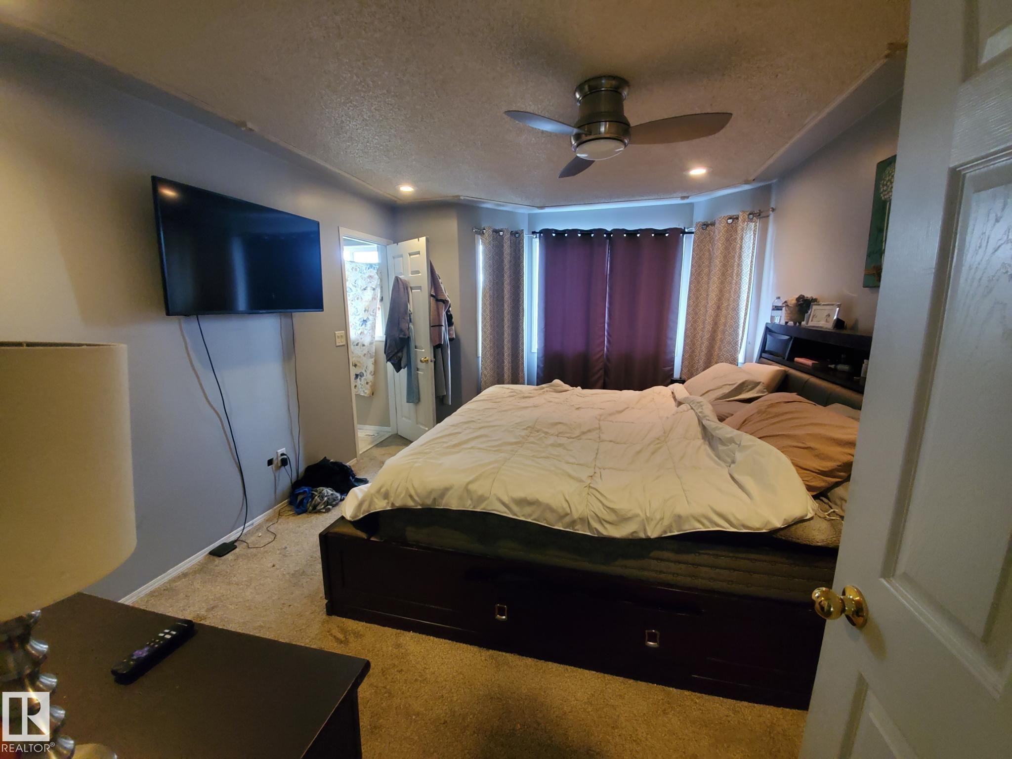 Carpeted room featuring a ceiling fan with integrated lighting, recessed ceiling lights, and bay windows - 53 Langley, Spruce Grove, AB