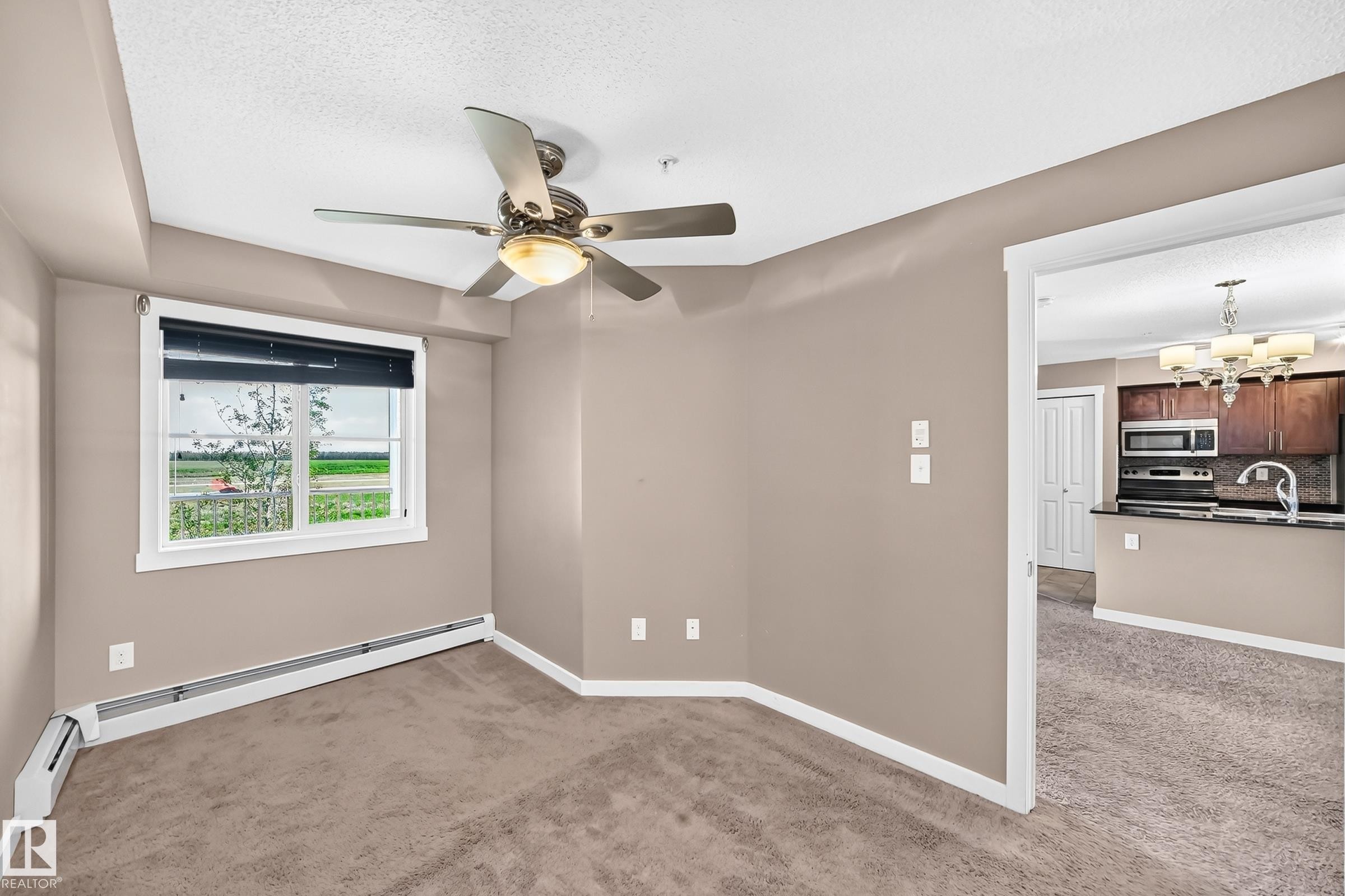 Carpeted room with a ceiling fan light fixture and window with blinds - 308 18126 77 Street, Edmonton, AB