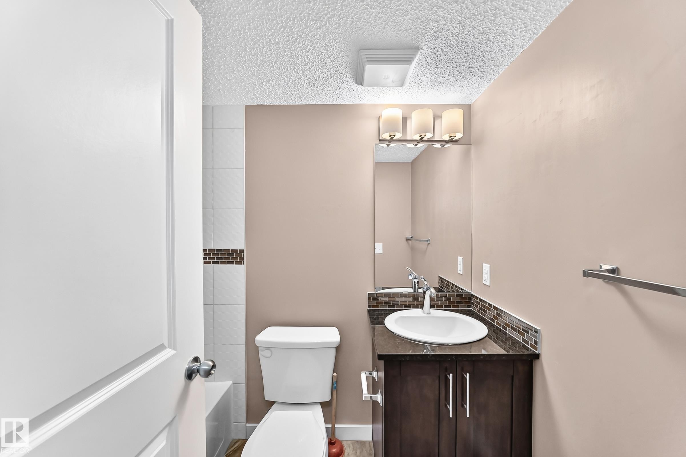 Bathroom featuring a dark wood-finish vanity with a white oval sink and a dark countertop - 308 18126 77 Street, Edmonton, AB
