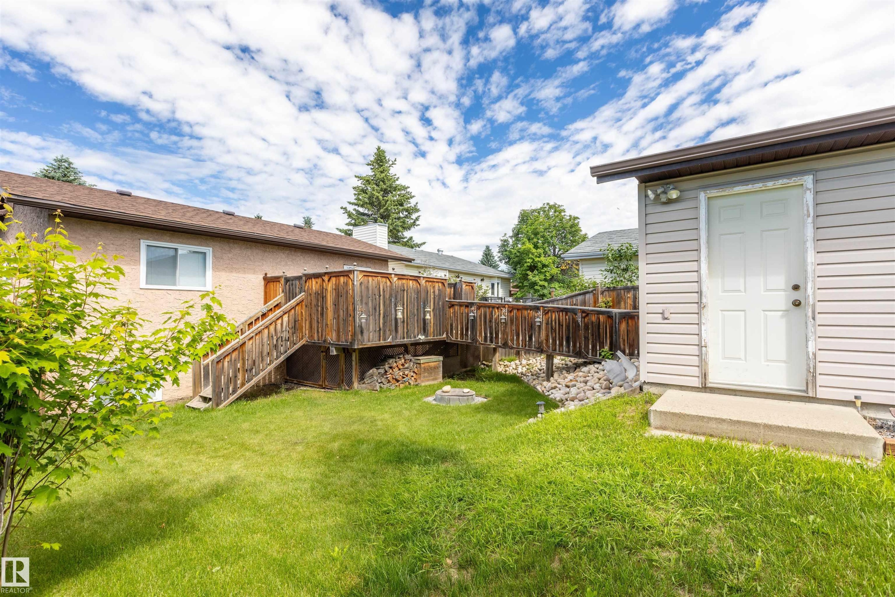 Spacious backyard featuring a multi-level wooden deck, a dedicated fire pit area, and a separate utility shed with siding - 3 Glenforest Crescent, Stony Plain, AB